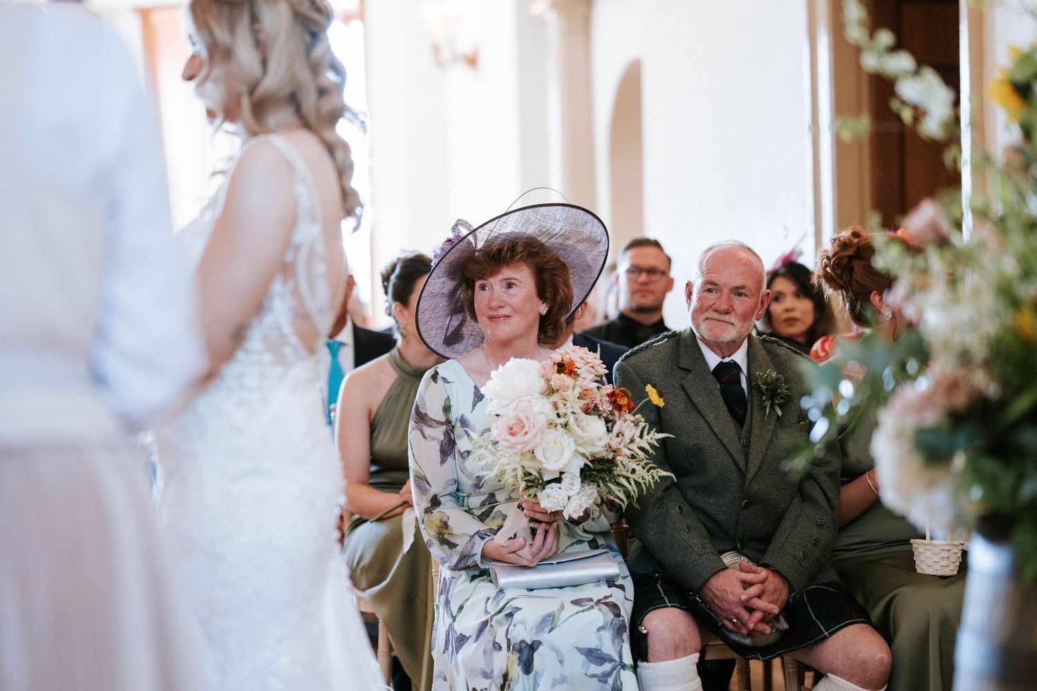 Wedding guests seated in rows during ceremony with decorative floral arrangements.