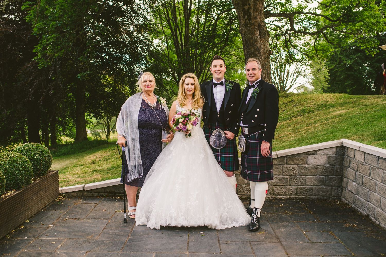 Wedding party walking along a tree-lined path at an outdoor venue.