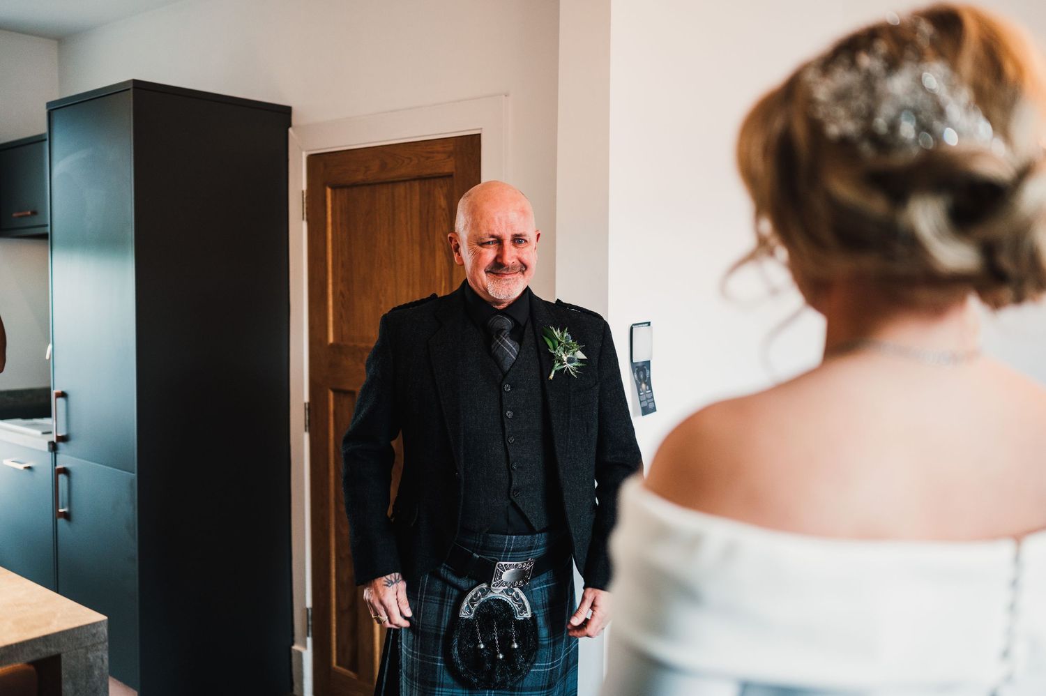 Emotional first look moment between bride and father in a modern indoor setting.