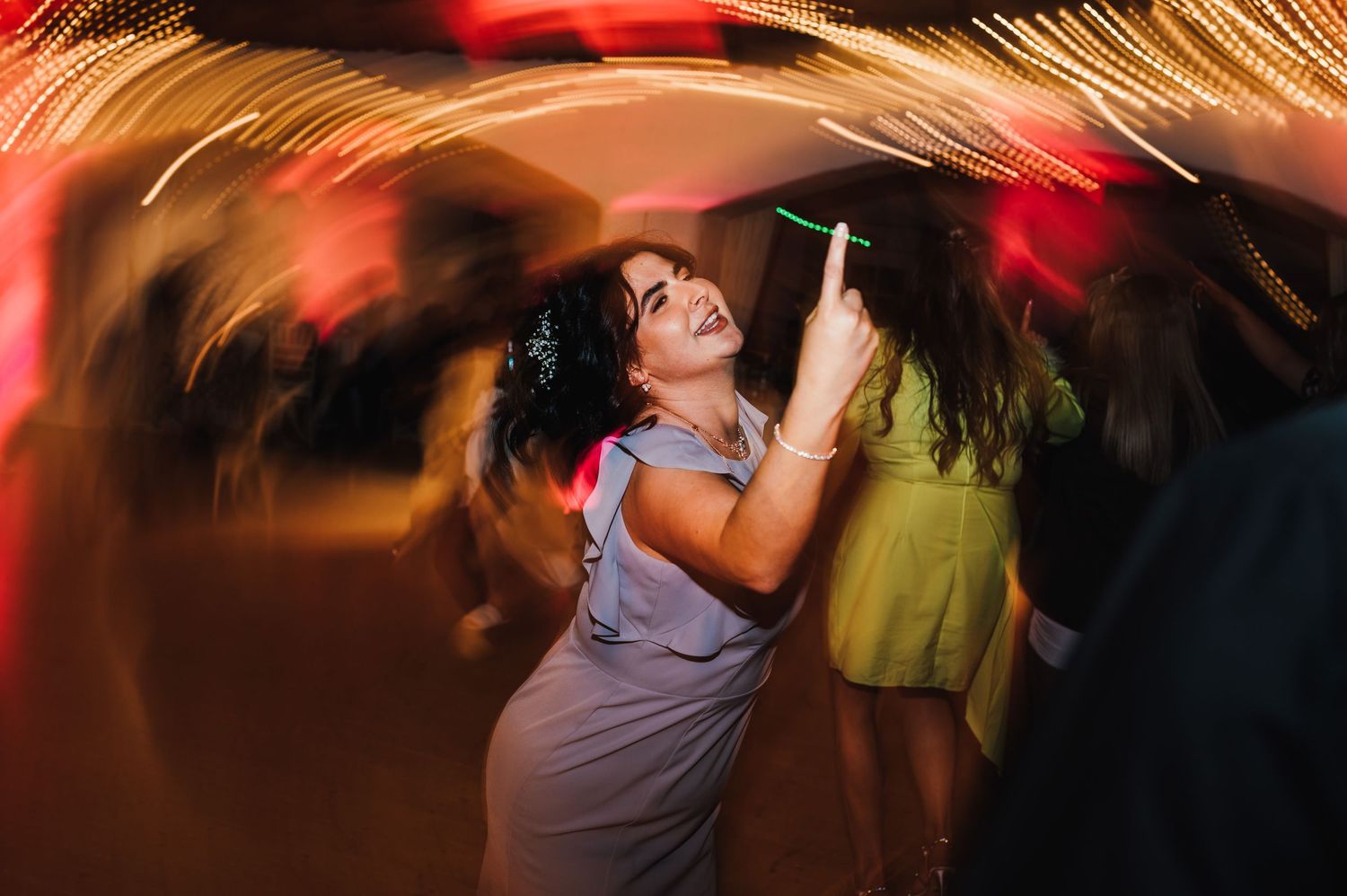 Blurred motion captures dancers moving energetically on a dimly lit dance floor with red lighting effects.