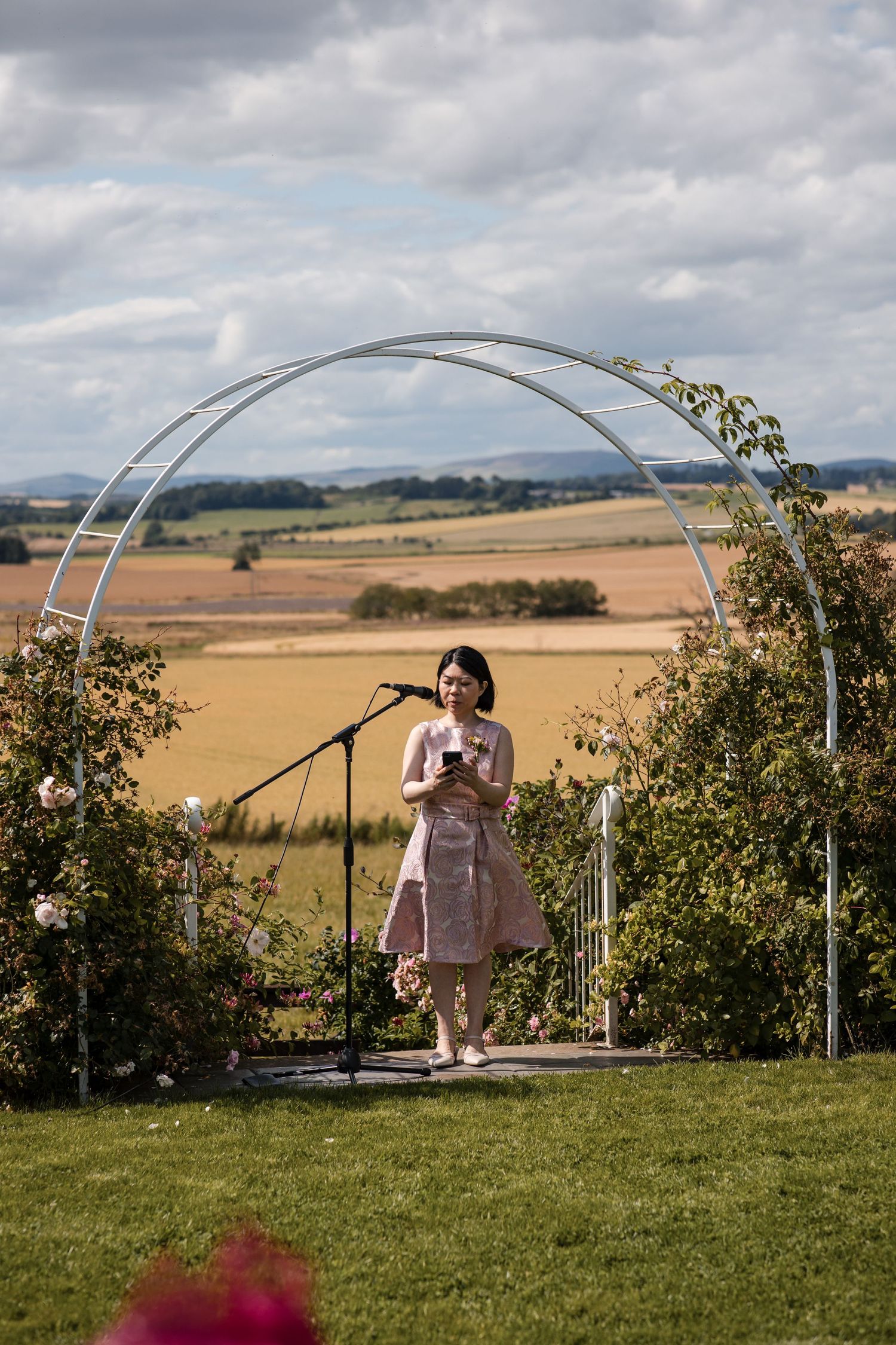 Metal arch structure set up on grassy hillside overlooking scenic countryside views.
