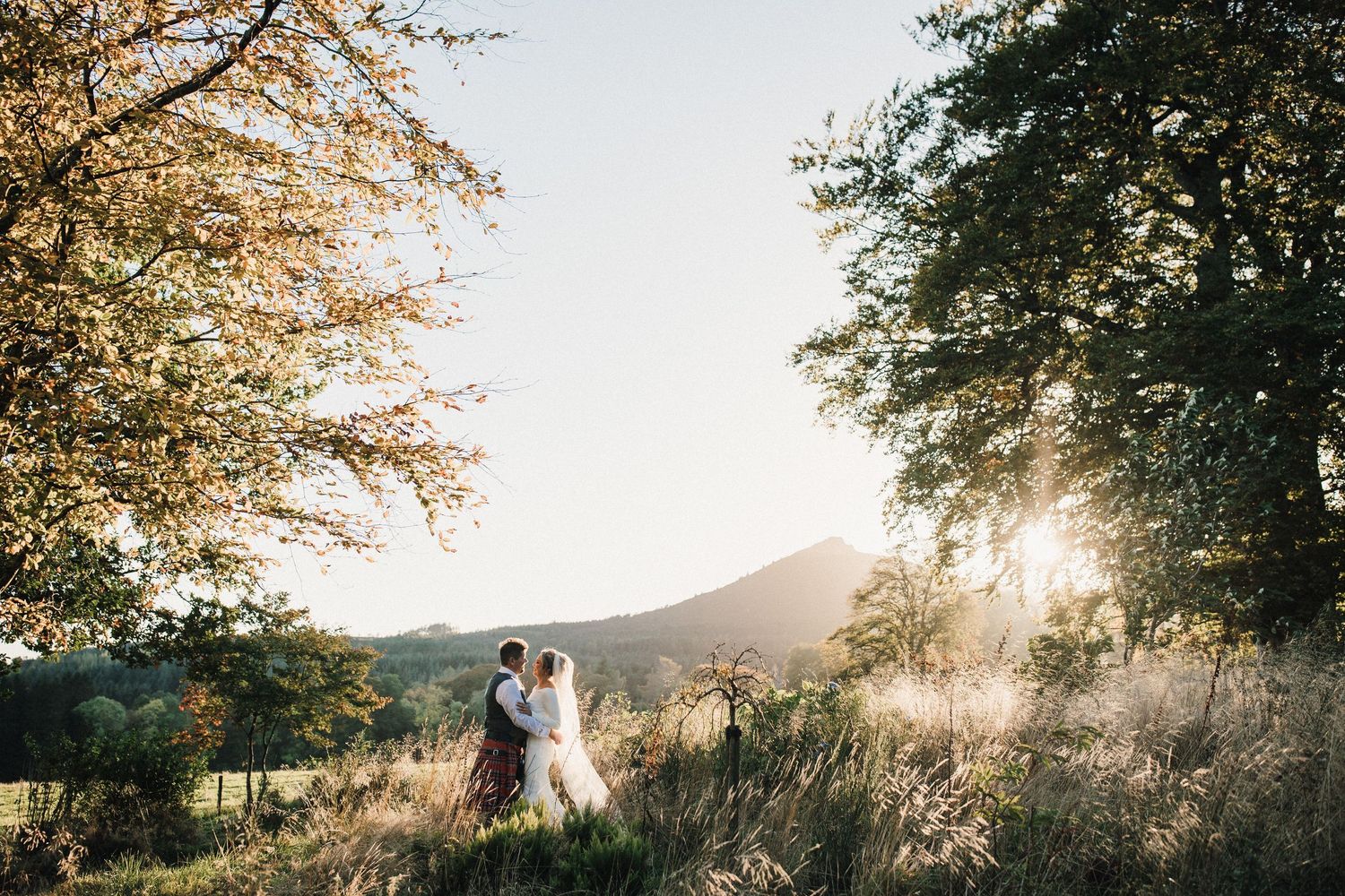 Aberdeen Wedding Photography. Golden sunlight filters through trees as a couple shares a romantic moment in nature.