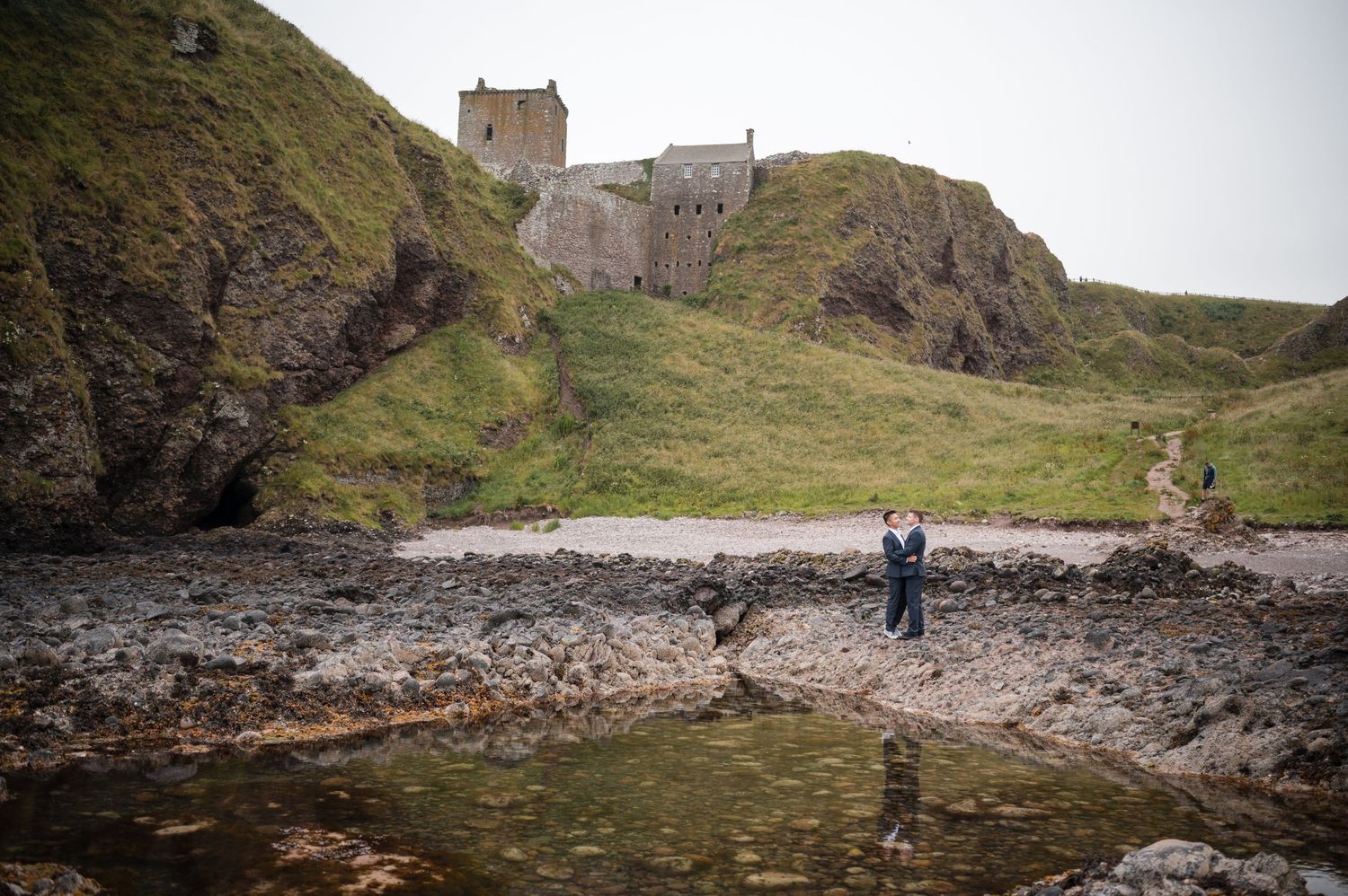 Same Sex Wedding Photography. Scenic coastal landscape with dramatic cliffs and rocky shoreline under cloudy skies.