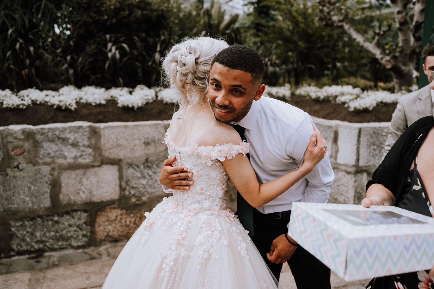 Wedding guests share heartfelt embraces during an outdoor garden reception.