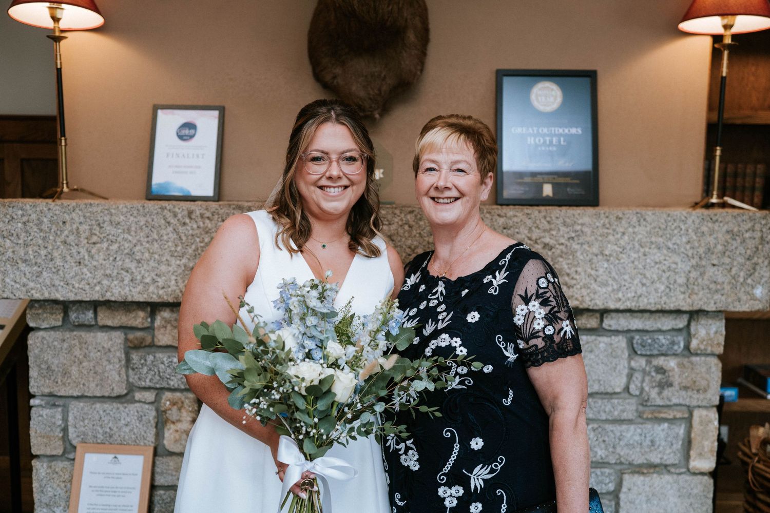 Wedding party members sharing joyful moments together in front of a stone wall backdrop.