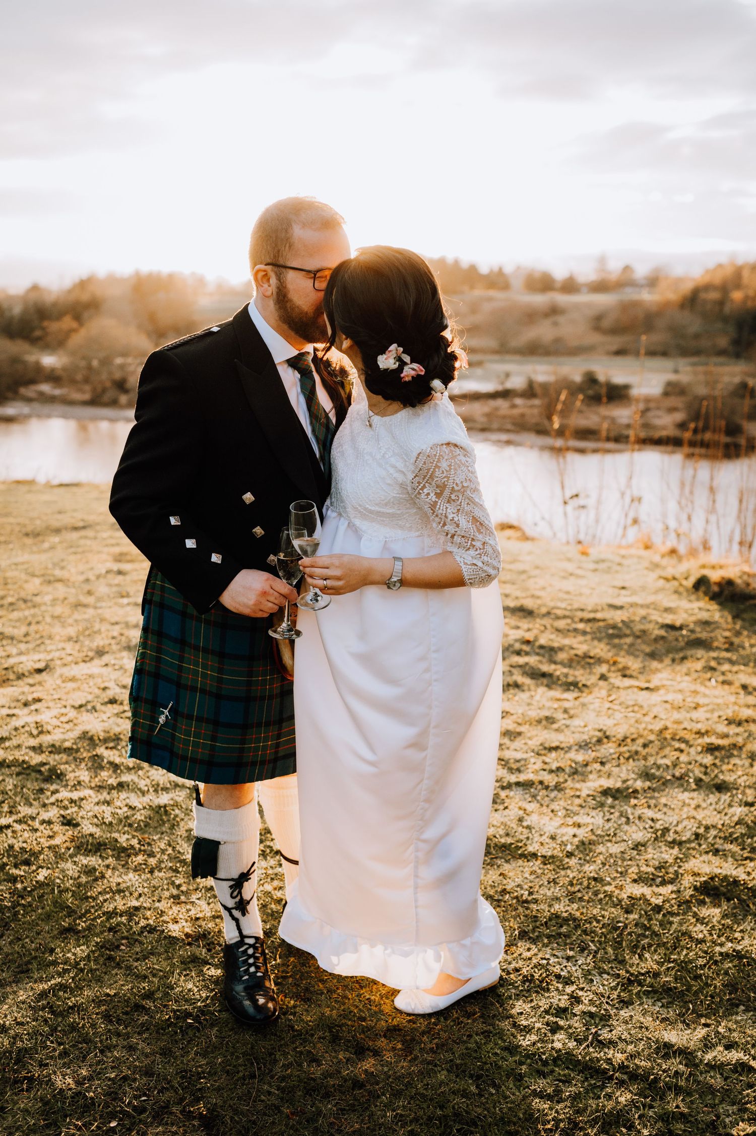 Intimate wedding moment captured at golden hour overlooking a serene lake.