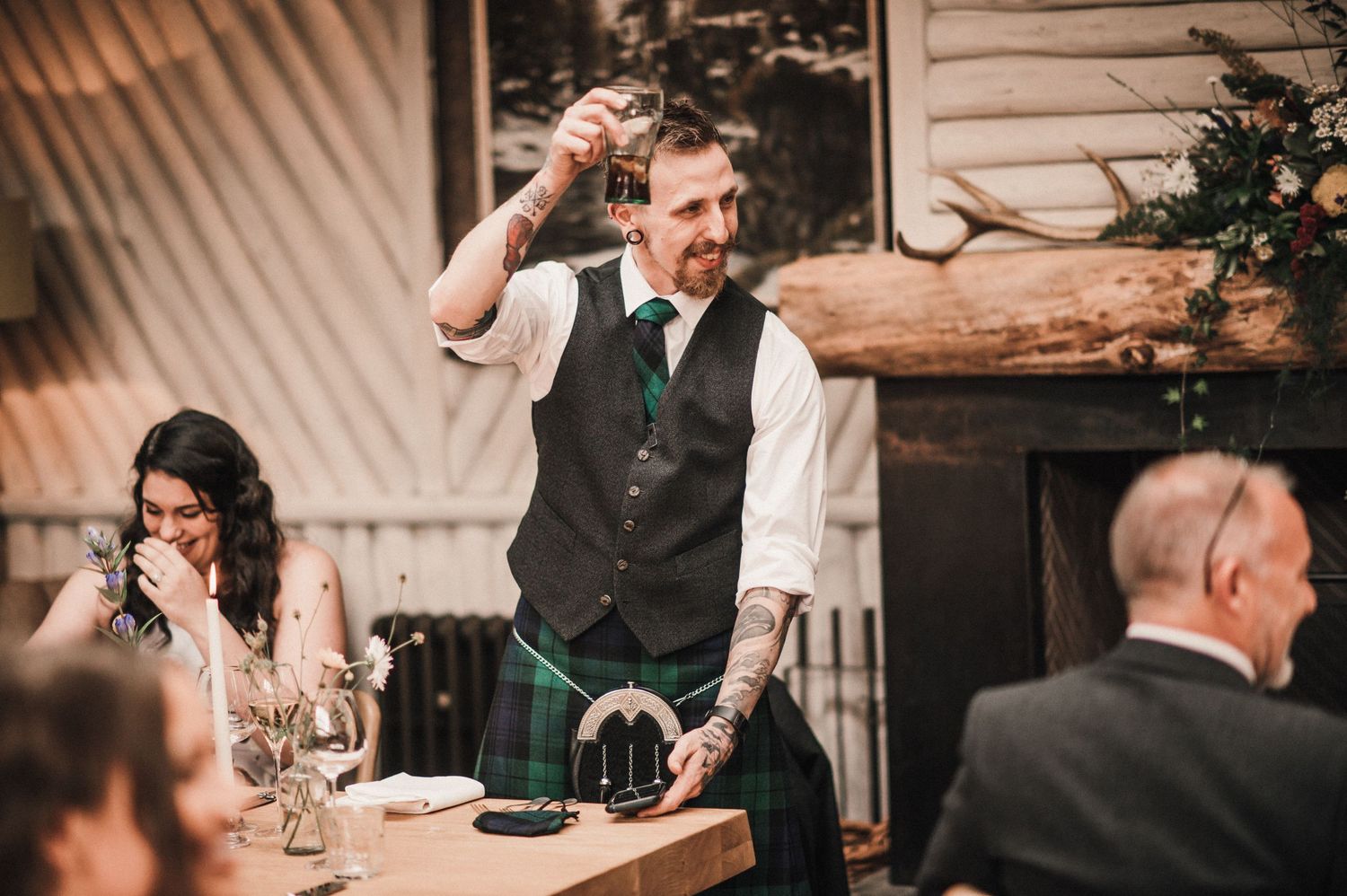Wedding speaker makes an animated toast while standing at reception dinner table.