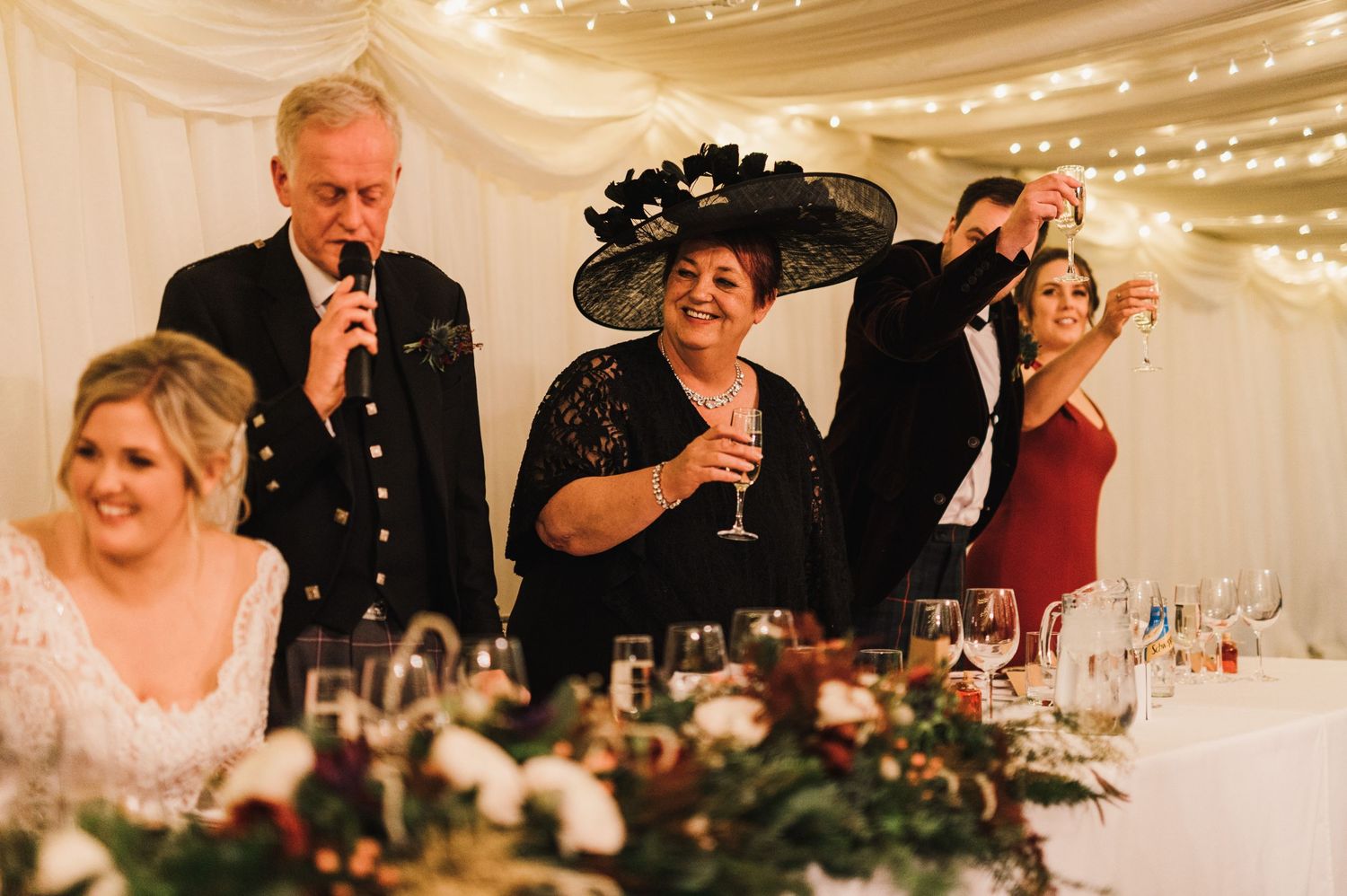 Wedding celebration at an elegant reception with guests raising glasses for a toast.