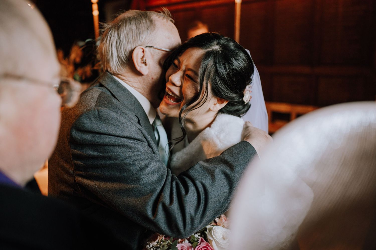 Emotional embrace shared during wedding reception in warm atmospheric lighting.