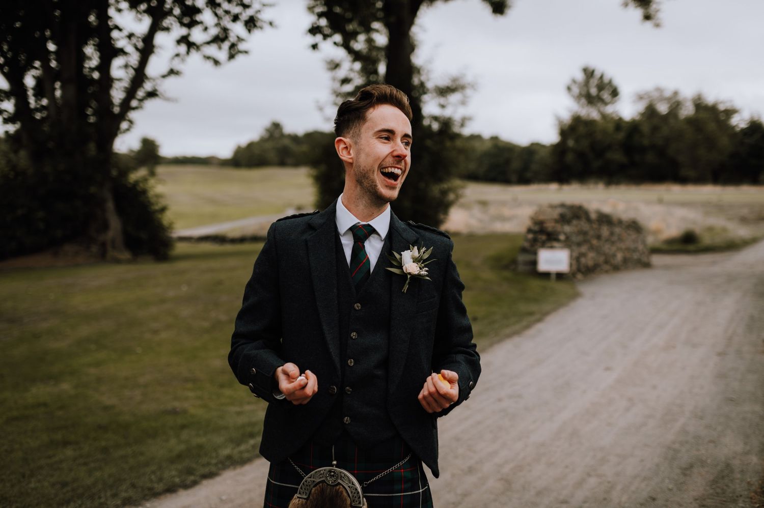 Traditional Scottish wedding attire with boutonniere in outdoor setting.