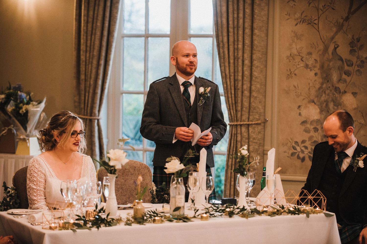 Wedding reception scene at head table with elegant floral centerpieces and decor.