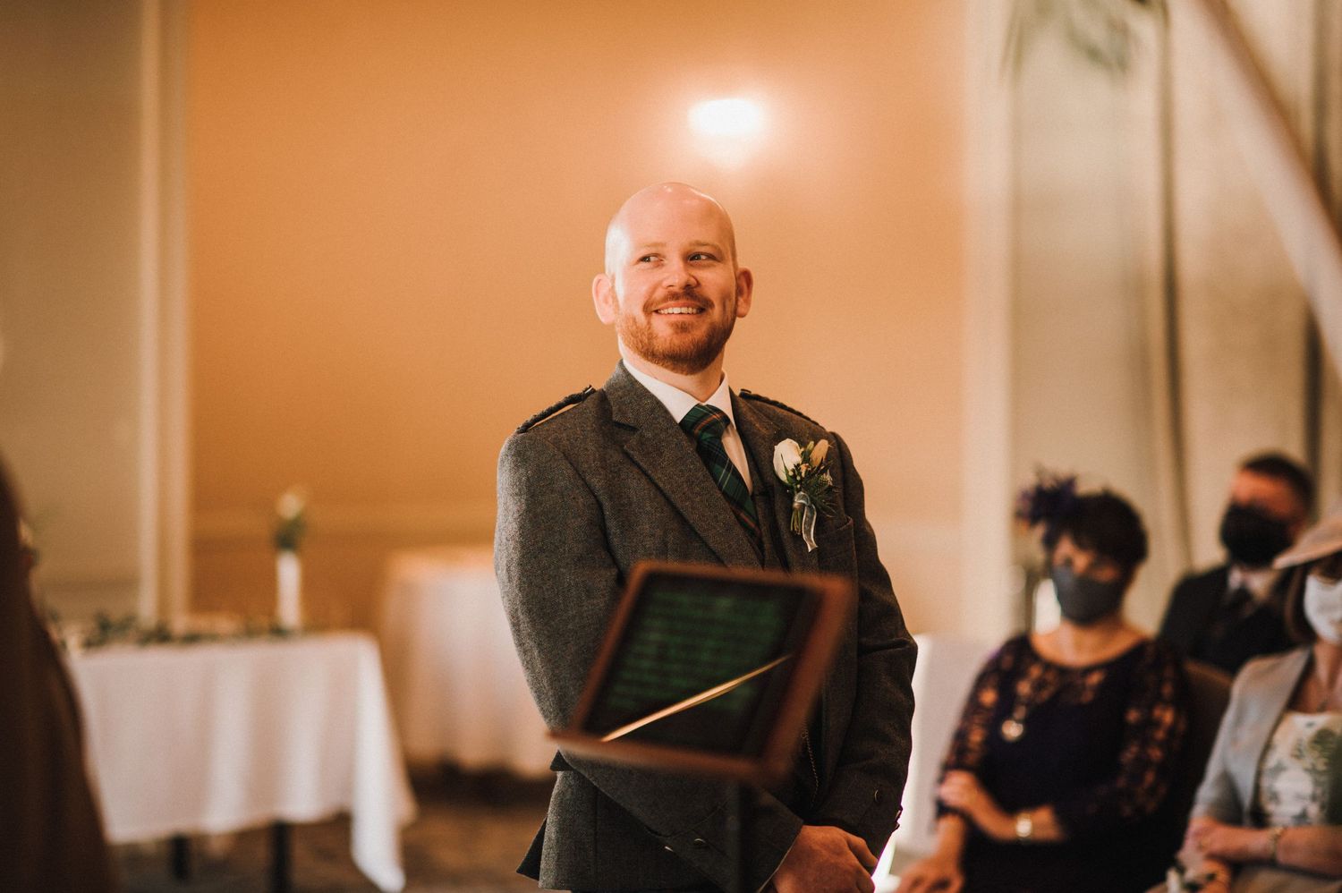 Wedding ceremony in a warmly lit room with traditional decor and floral arrangements.