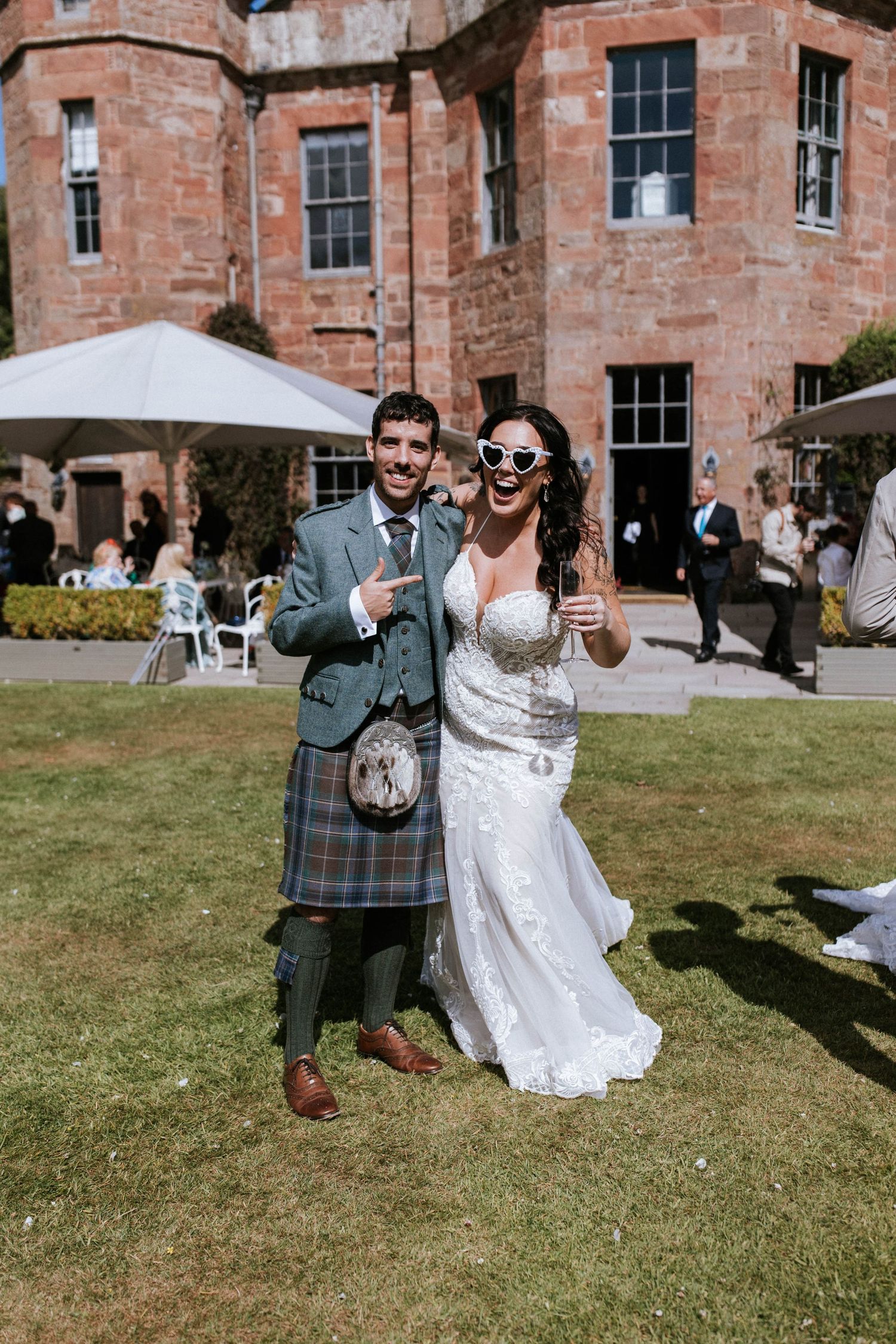 Fasque Castle Wedding Photography. Wedding celebration outside historic brick building with guests enjoying festivities on lawn.