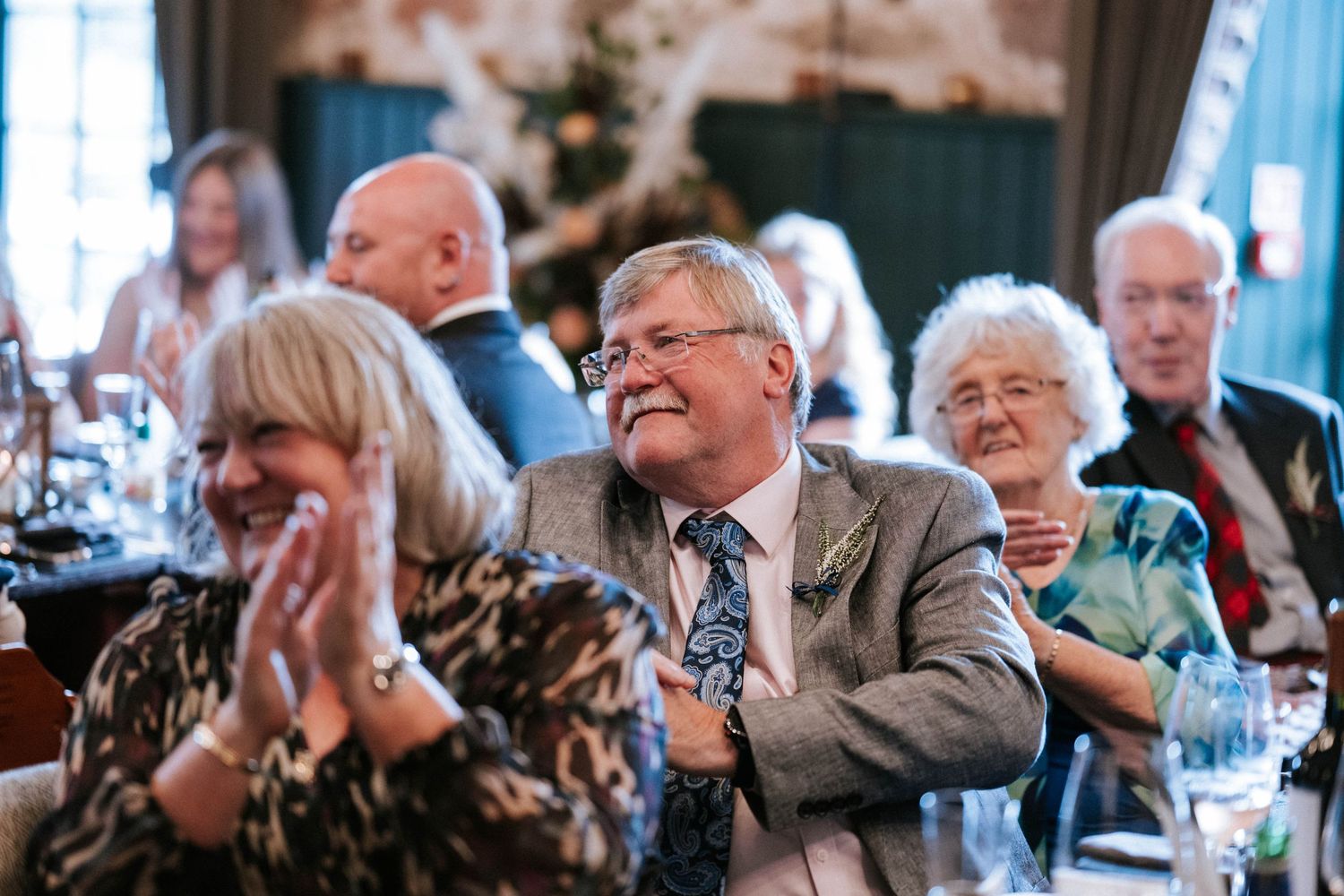 Wedding guests laugh and applaud during reception speeches and toasts.