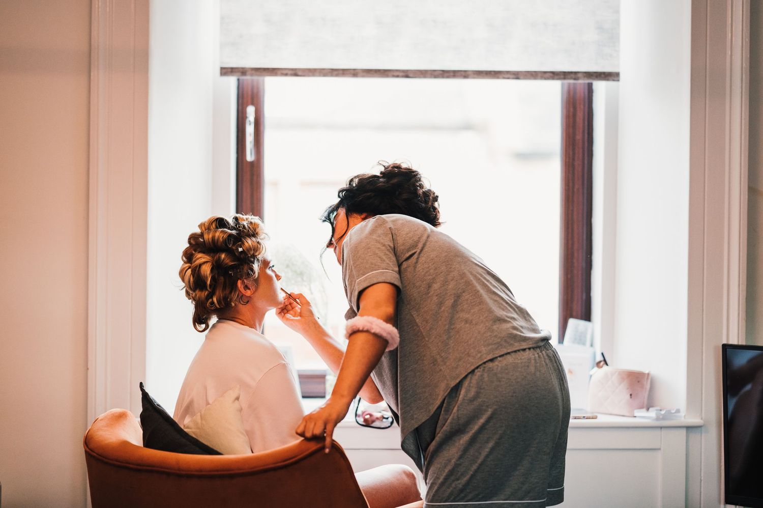 A group of people getting ready in a bright room with white walls and windows.