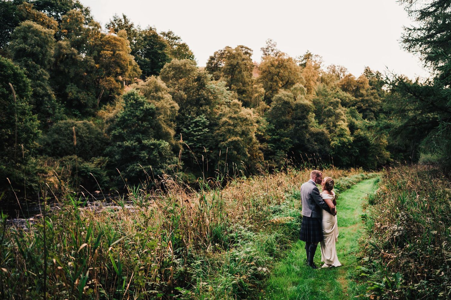 Scenic outdoor garden path surrounded by lush greenery and trees in golden afternoon light.