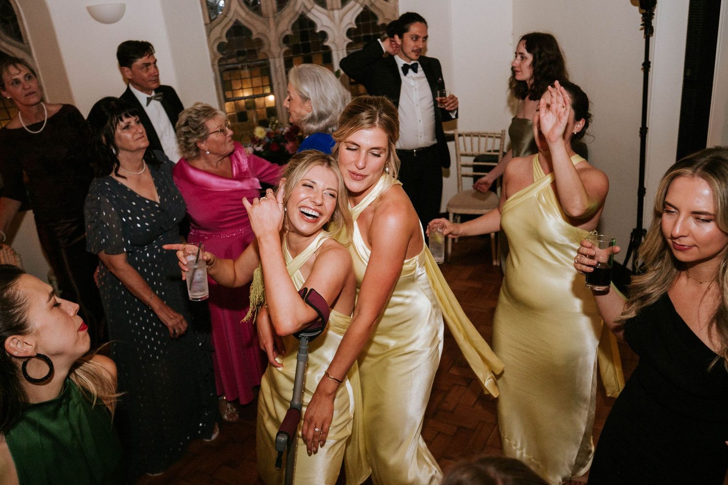 Wedding guests dancing and celebrating in an elegant venue with string lights overhead.