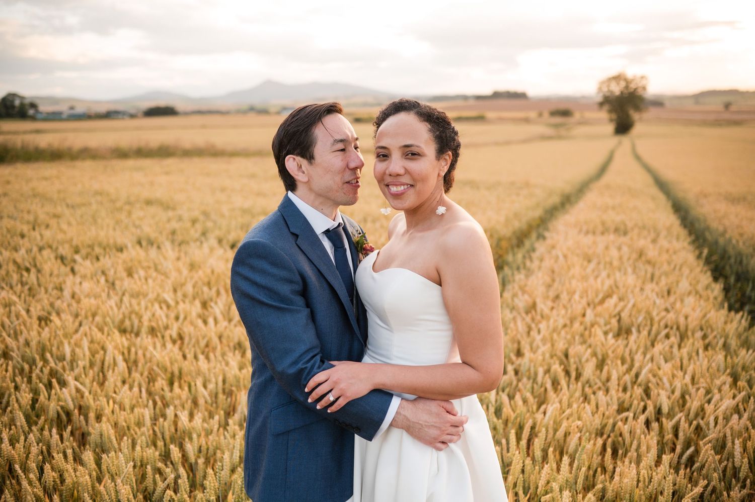Romantic couple embracing in a golden wheat field during sunset.