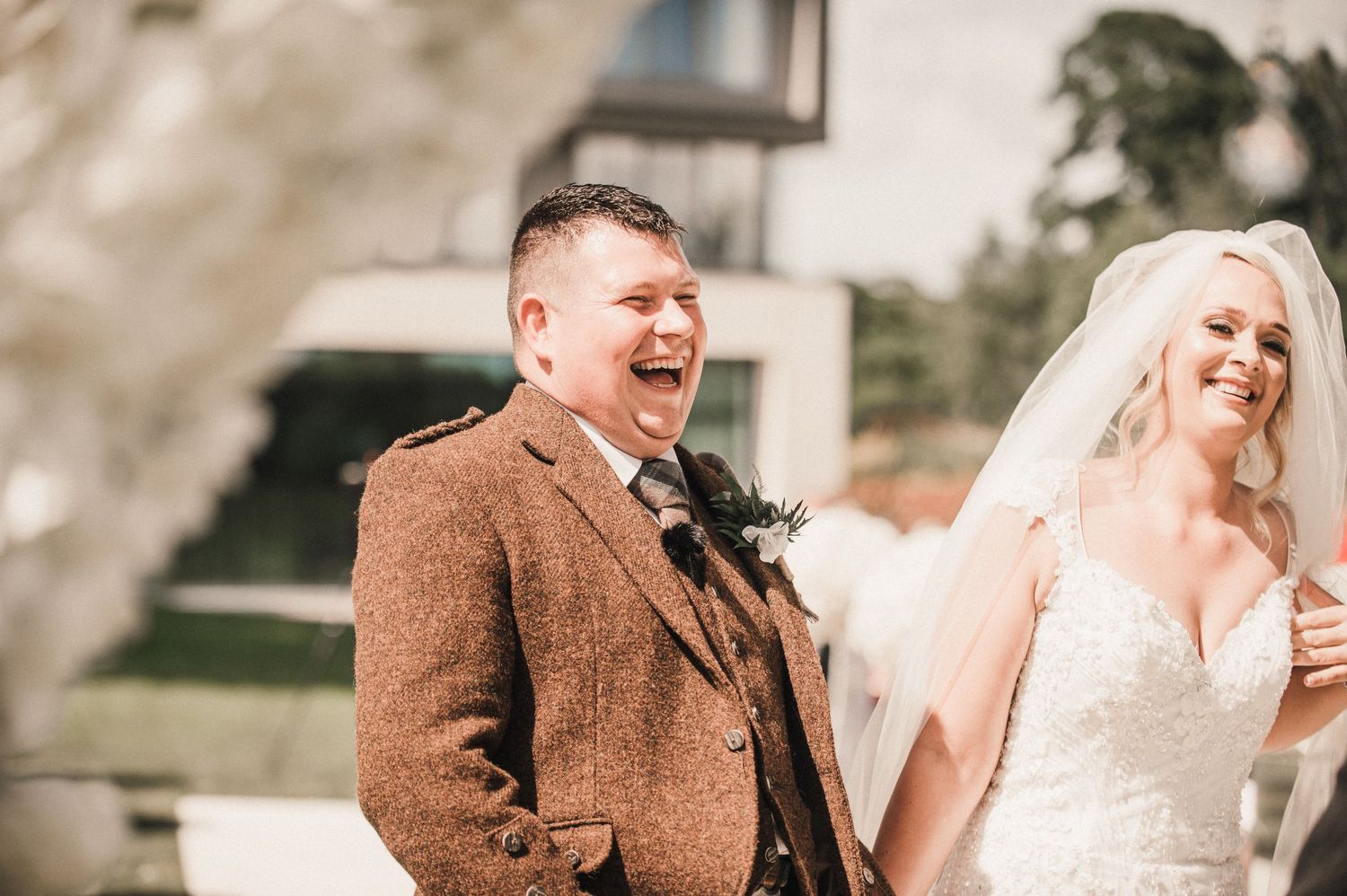 Joyful moment captured during outdoor wedding ceremony under floral arch.