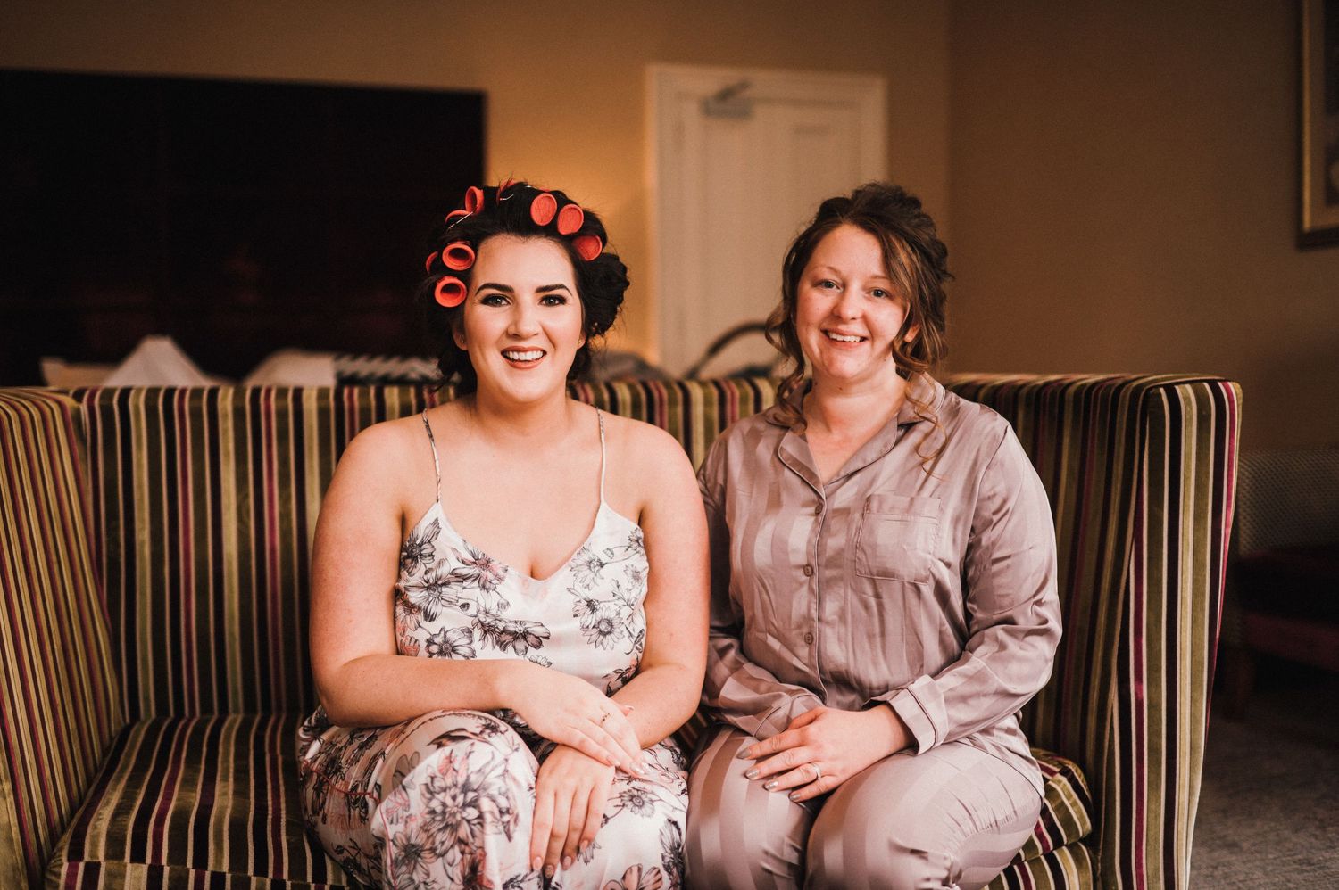 Two people sitting on striped couch during wedding preparations.