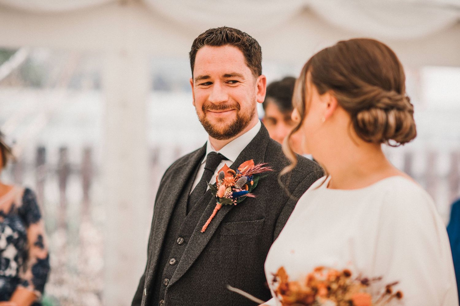 Wedding couple sharing a joyful moment under a white tent during their celebration.