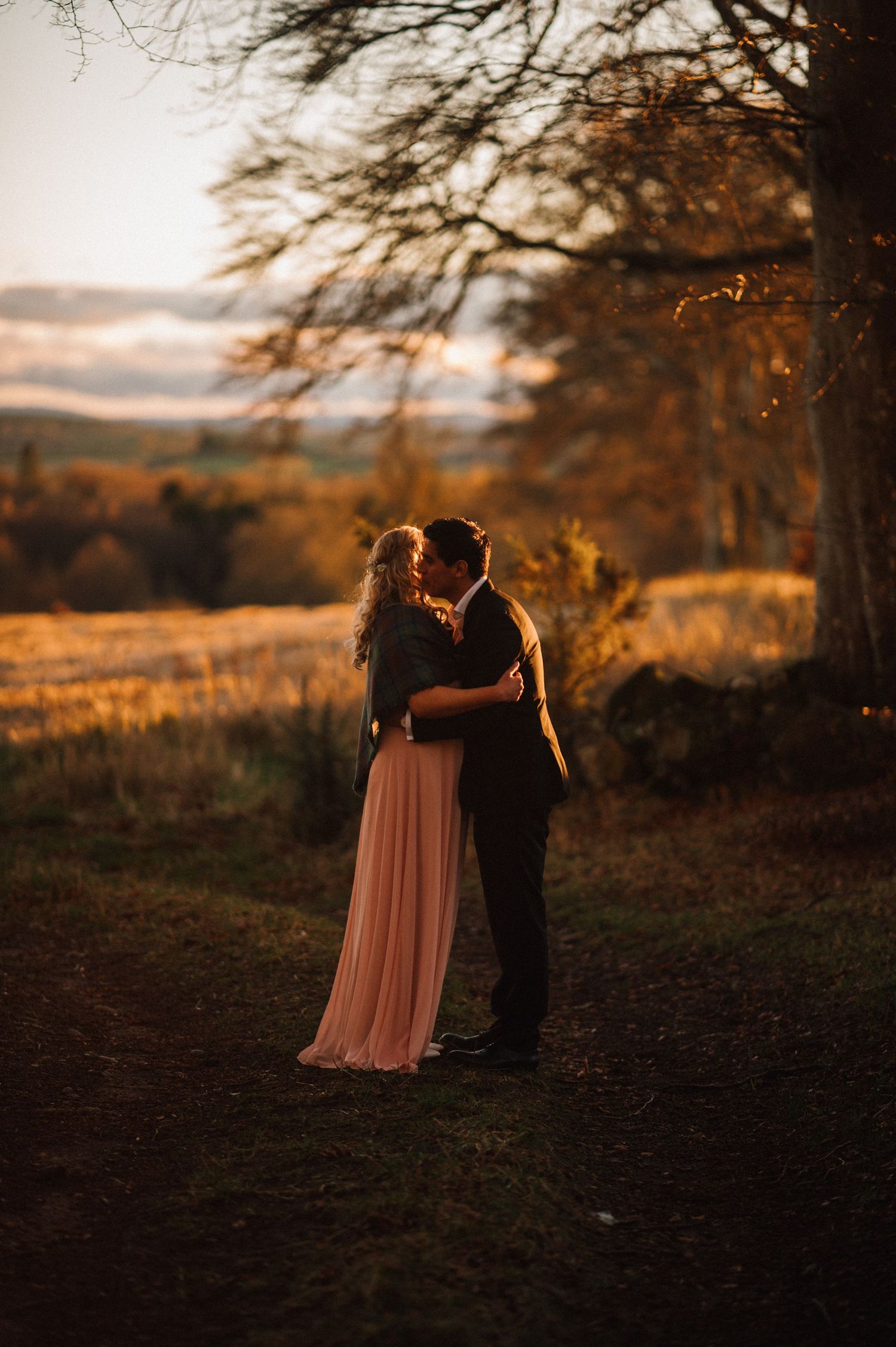 A romantic sunset moment between two people in formal wear surrounded by autumn colors.