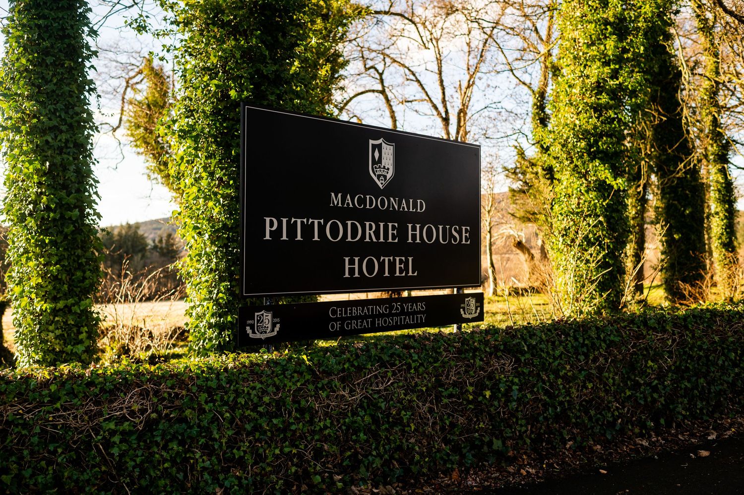 Elegant Pittodrie House Hotel entrance sign surrounded by lush green ivy.