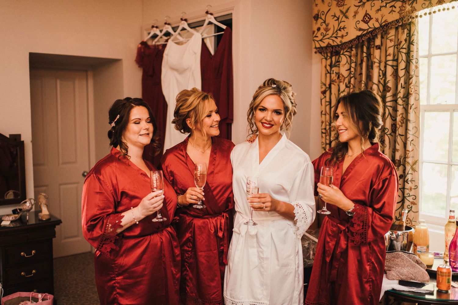 Wedding preparation scene with attendants in matching red satin robes.