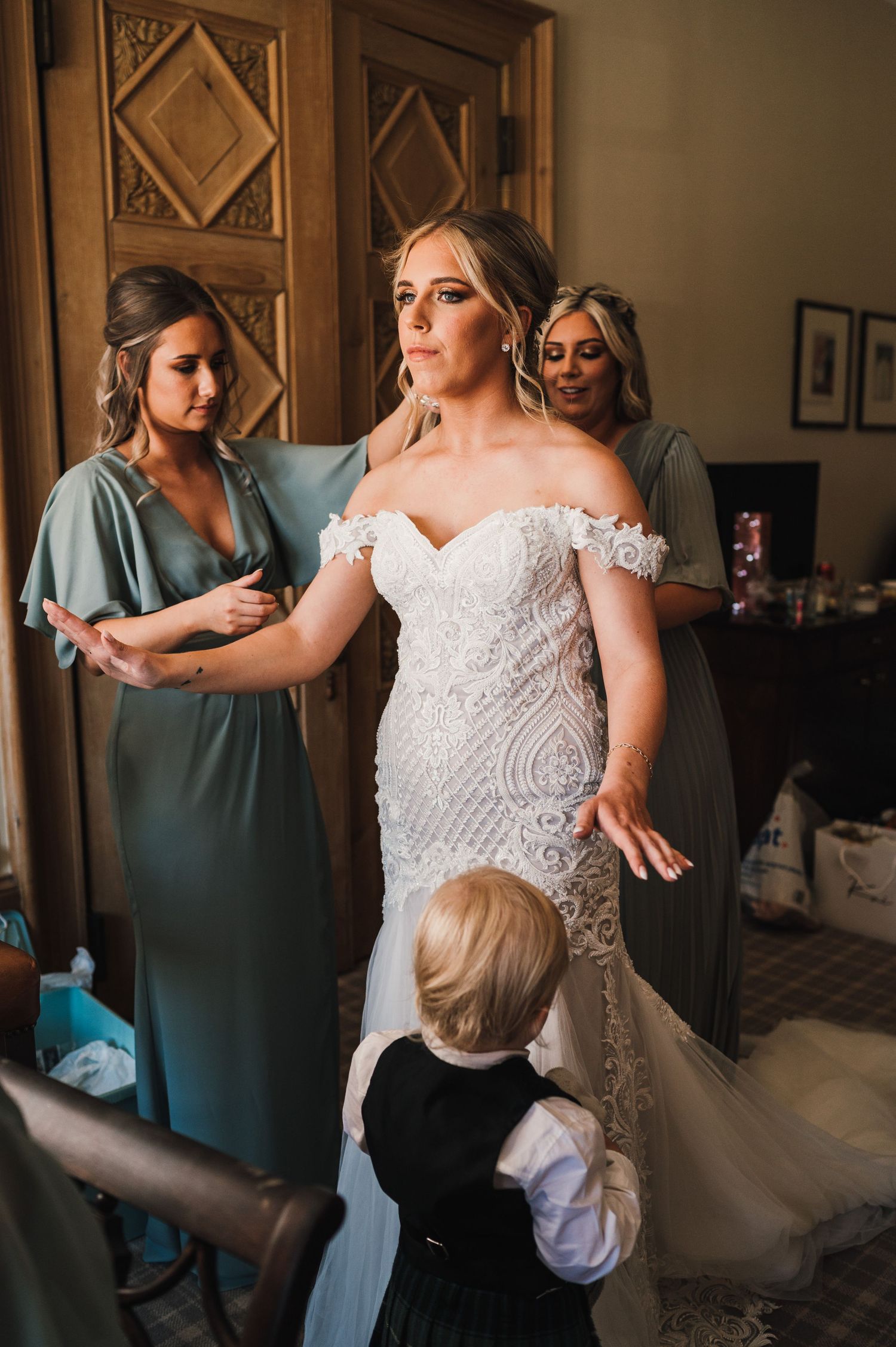 Wedding dress fitting moment with attendants helping adjust the gown.