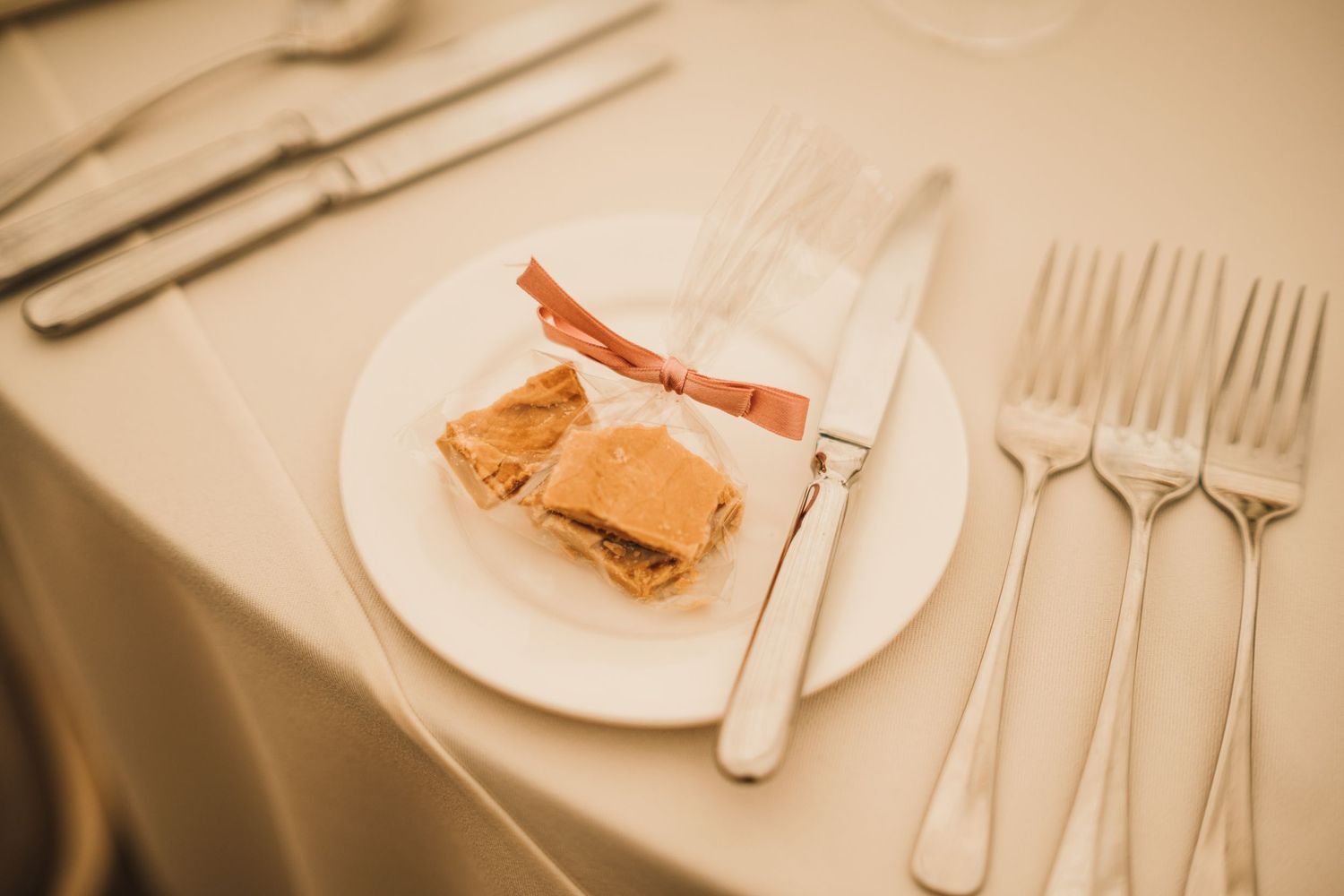 Place setting at a formal dinner with silverware and a small appetizer on white plate.