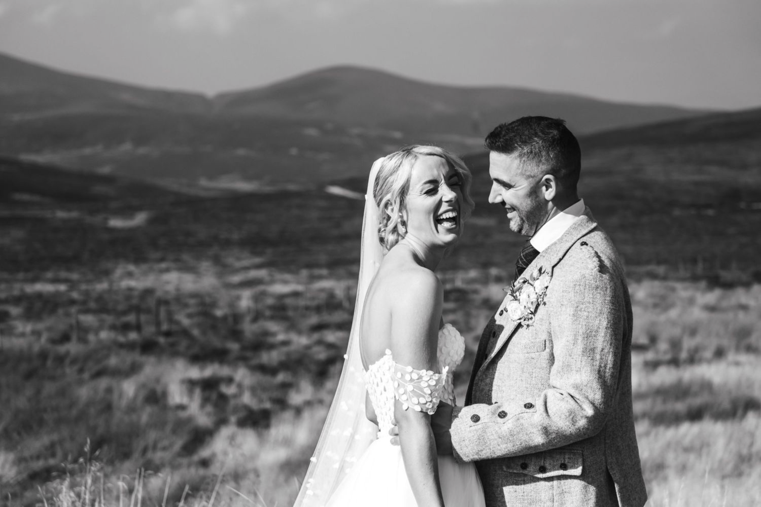 A romantic wedding photoshoot in a scenic mountain landscape with rolling hills and natural terrain in the background.