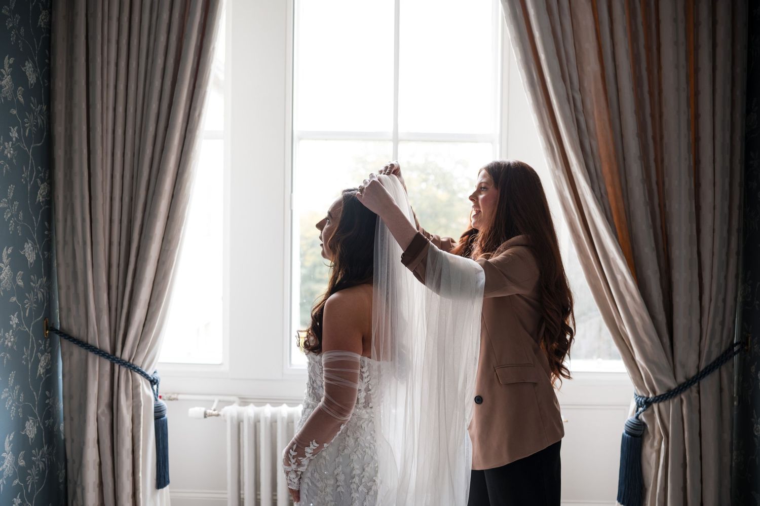 Aberdeen Wedding Photography. Silhouetted figures pose dramatically against bright window with curtains.