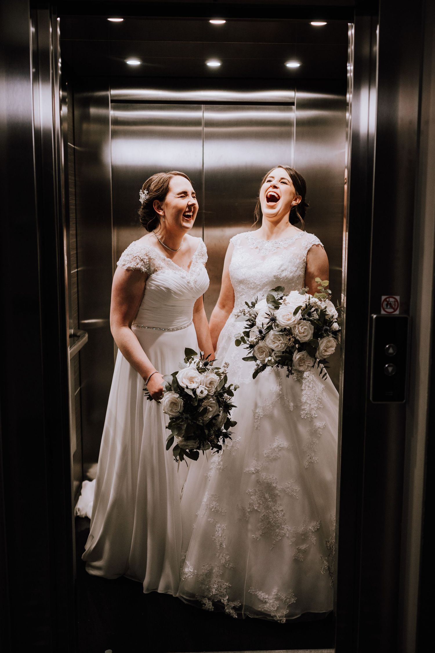 Candid moment of laughter in an elevator with white wedding dresses and bouquets. Meldrum House Wedding Photography.