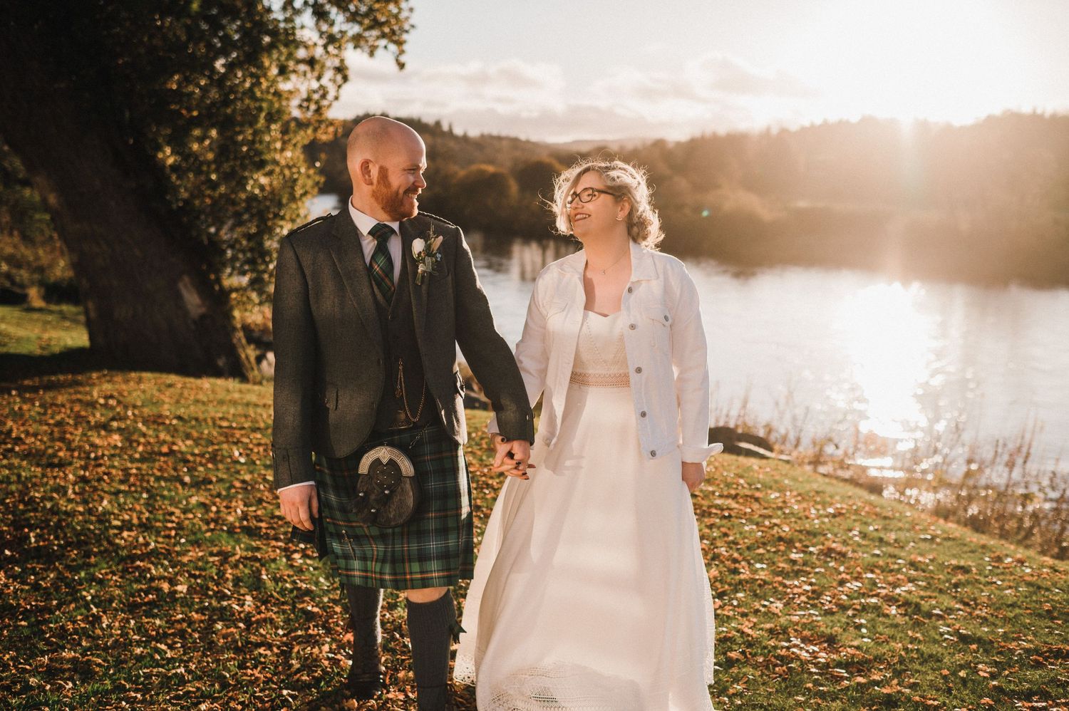 Romantic sunset wedding photos by a lake with Scottish Highland wedding attire.