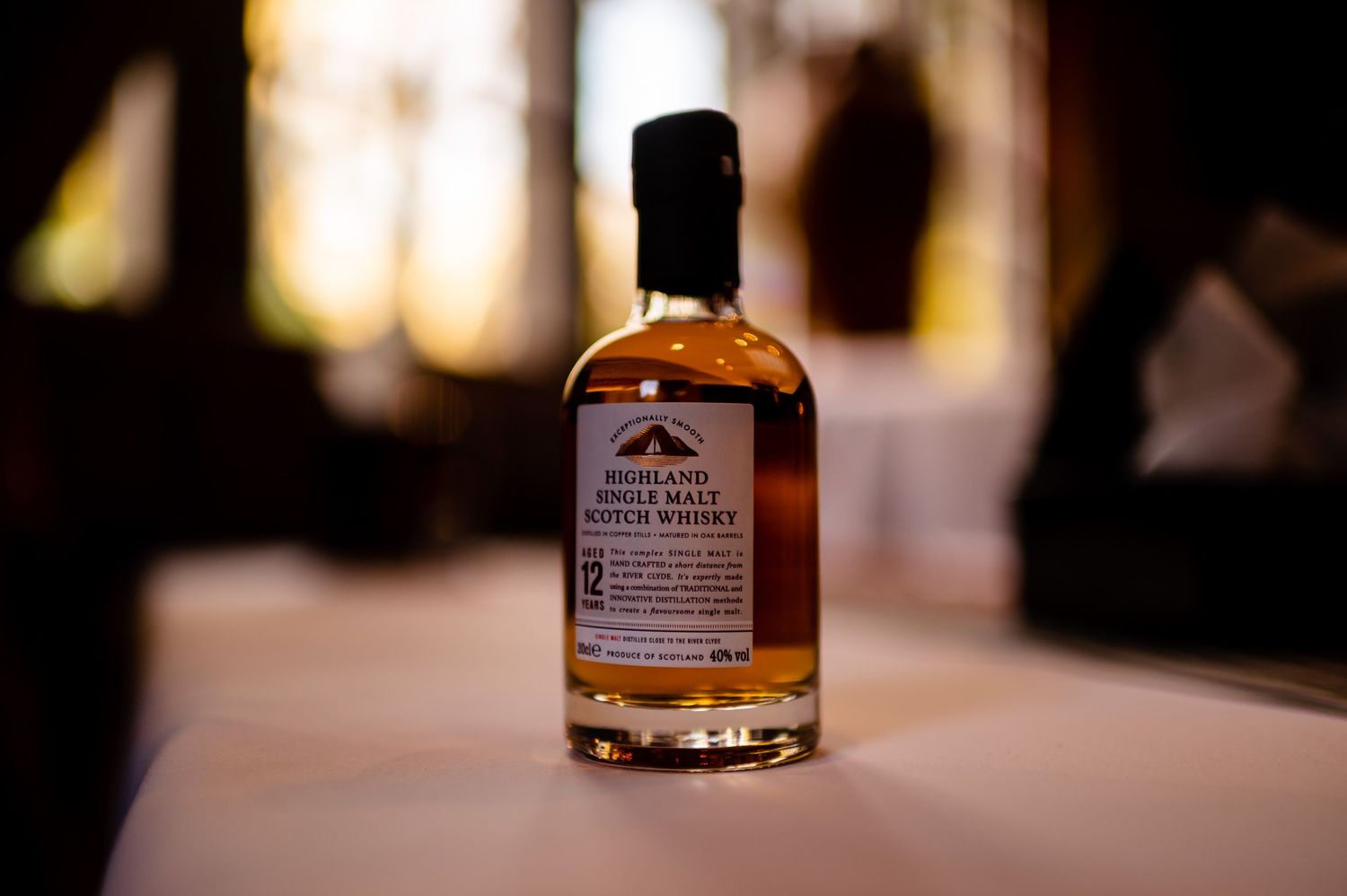 Close-up of whiskey bottle on table with soft focus background.
