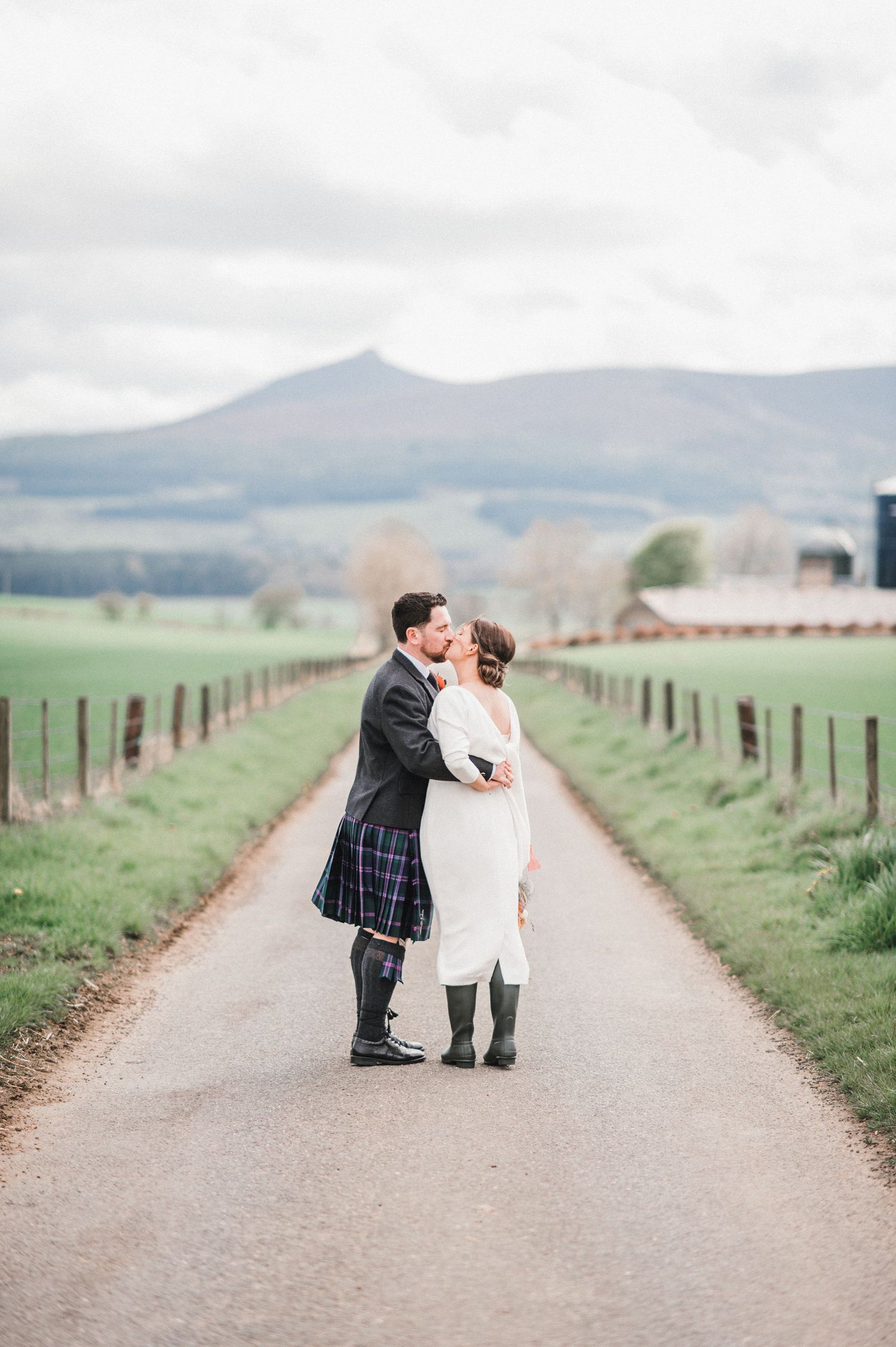 Romantic wedding portrait on a country road with dramatic mountain landscape in background.