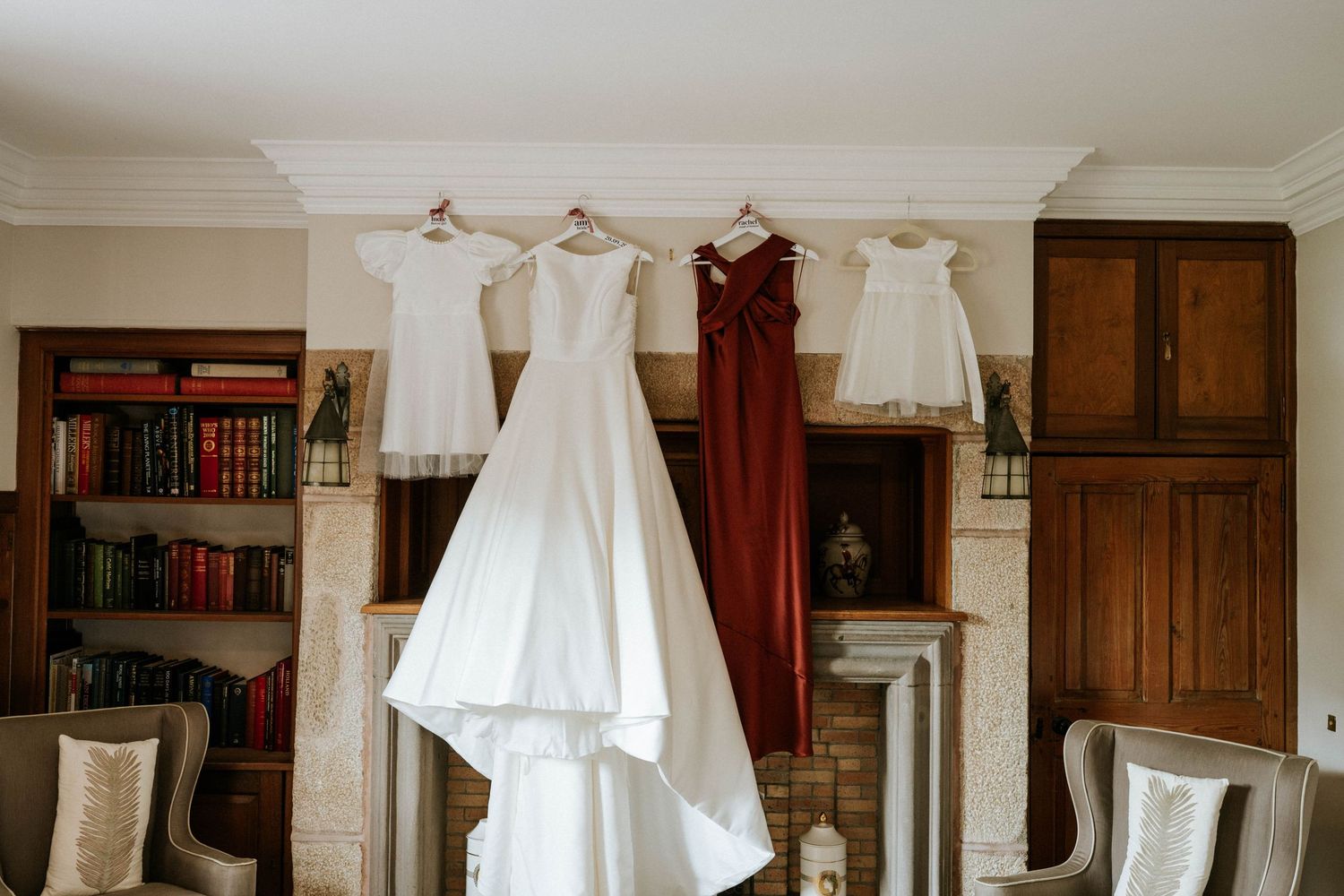 Wedding dress hanging in an elegant room with wood paneling and built-in bookshelves.