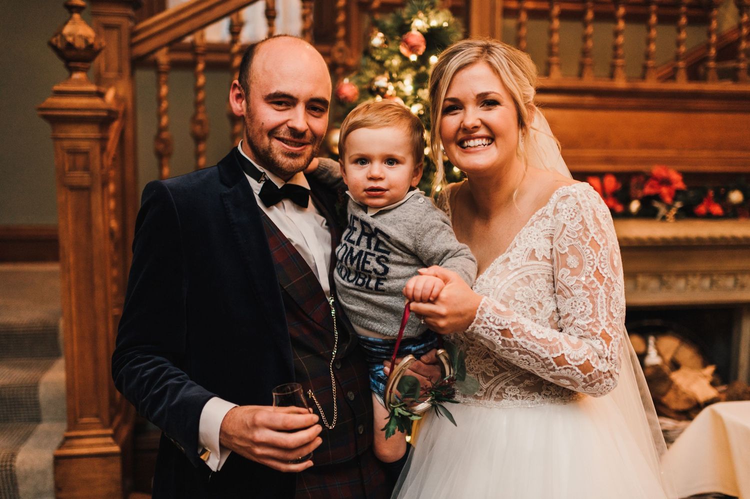 An indoor celebration scene with festive Christmas decorations and wooden staircase in the background.