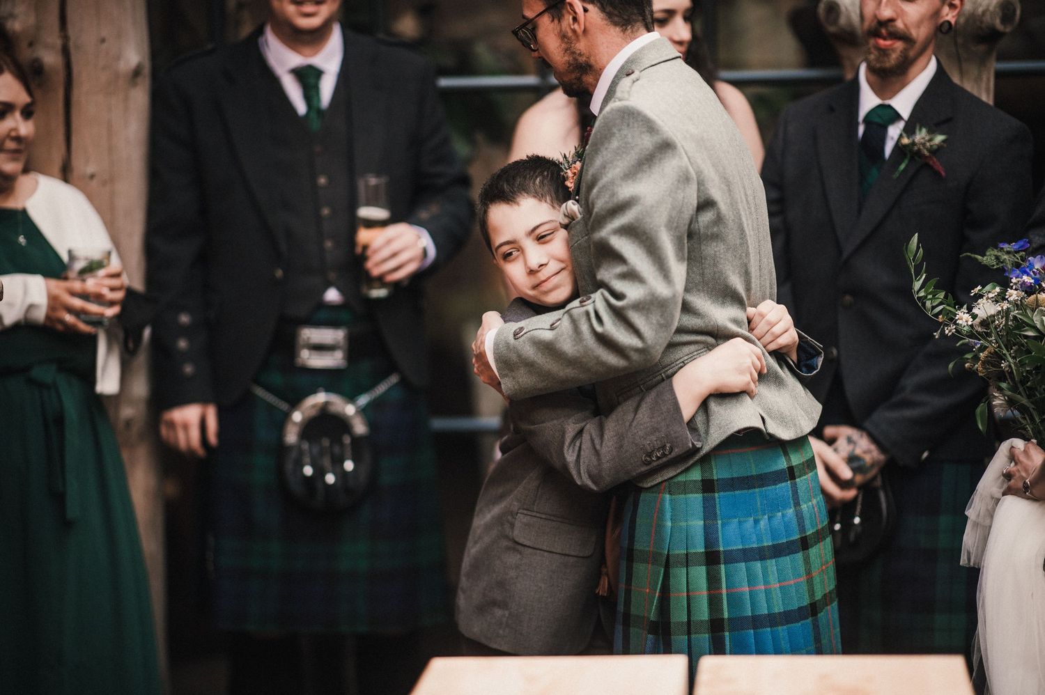 Traditional Scottish wedding celebration with kilted guests embracing.