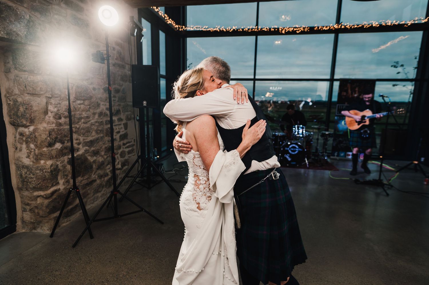 Couple sharing a romantic dance embrace in an industrial venue with large windows and natural lighting.