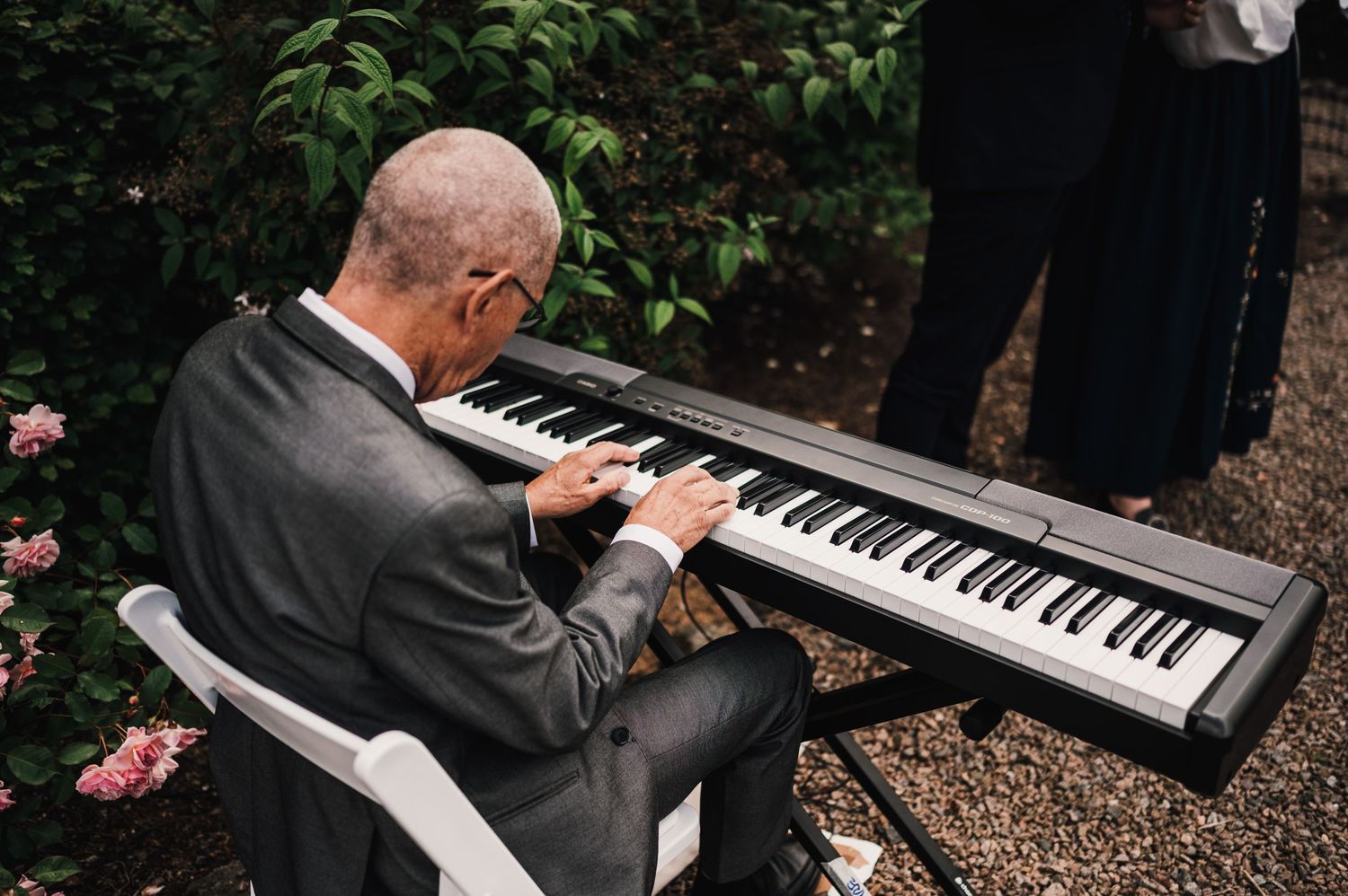 Musician playing digital piano at outdoor garden wedding event.