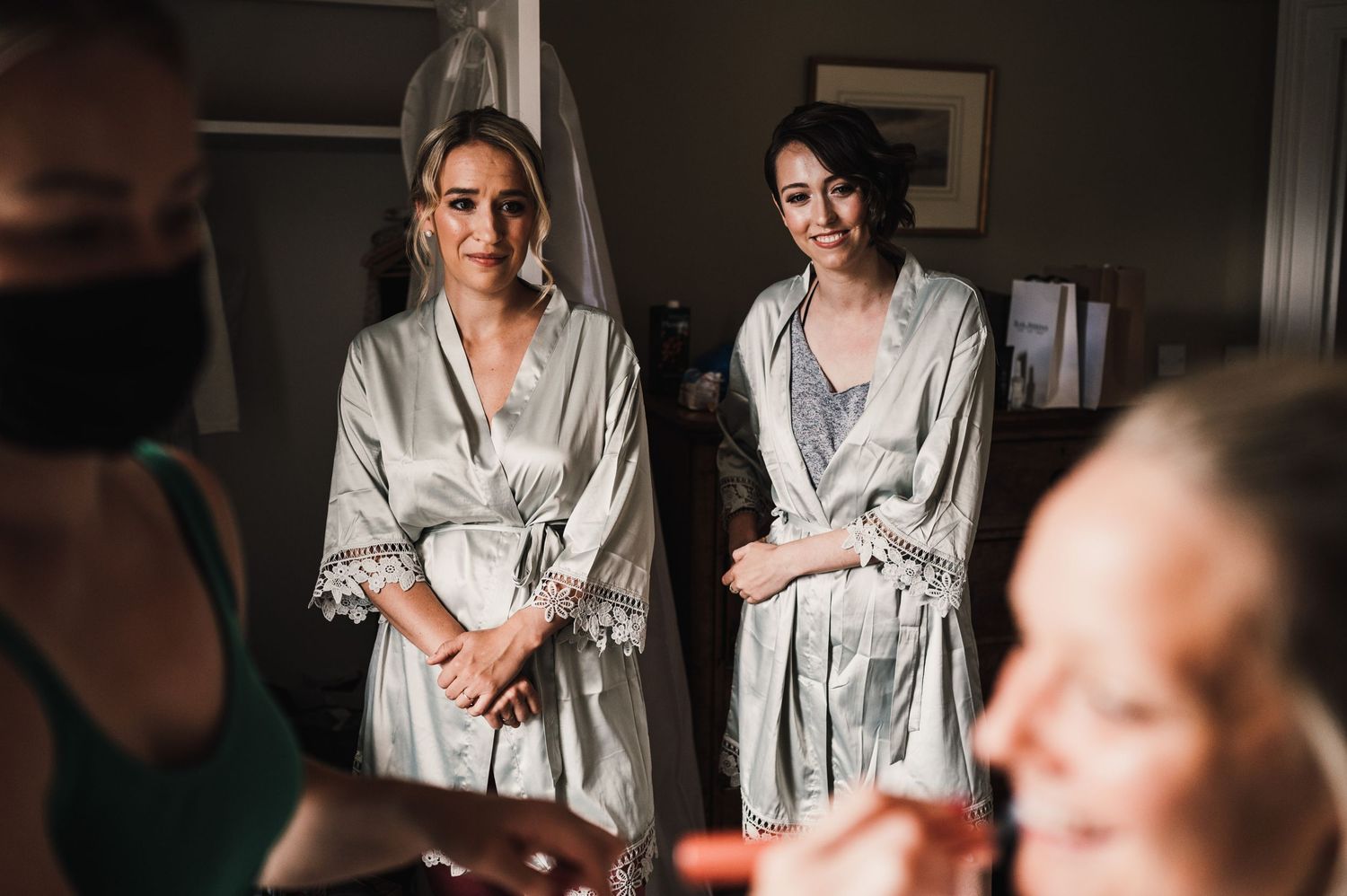 Getting ready scene in silver silk robes within an elegantly furnished bedroom.
