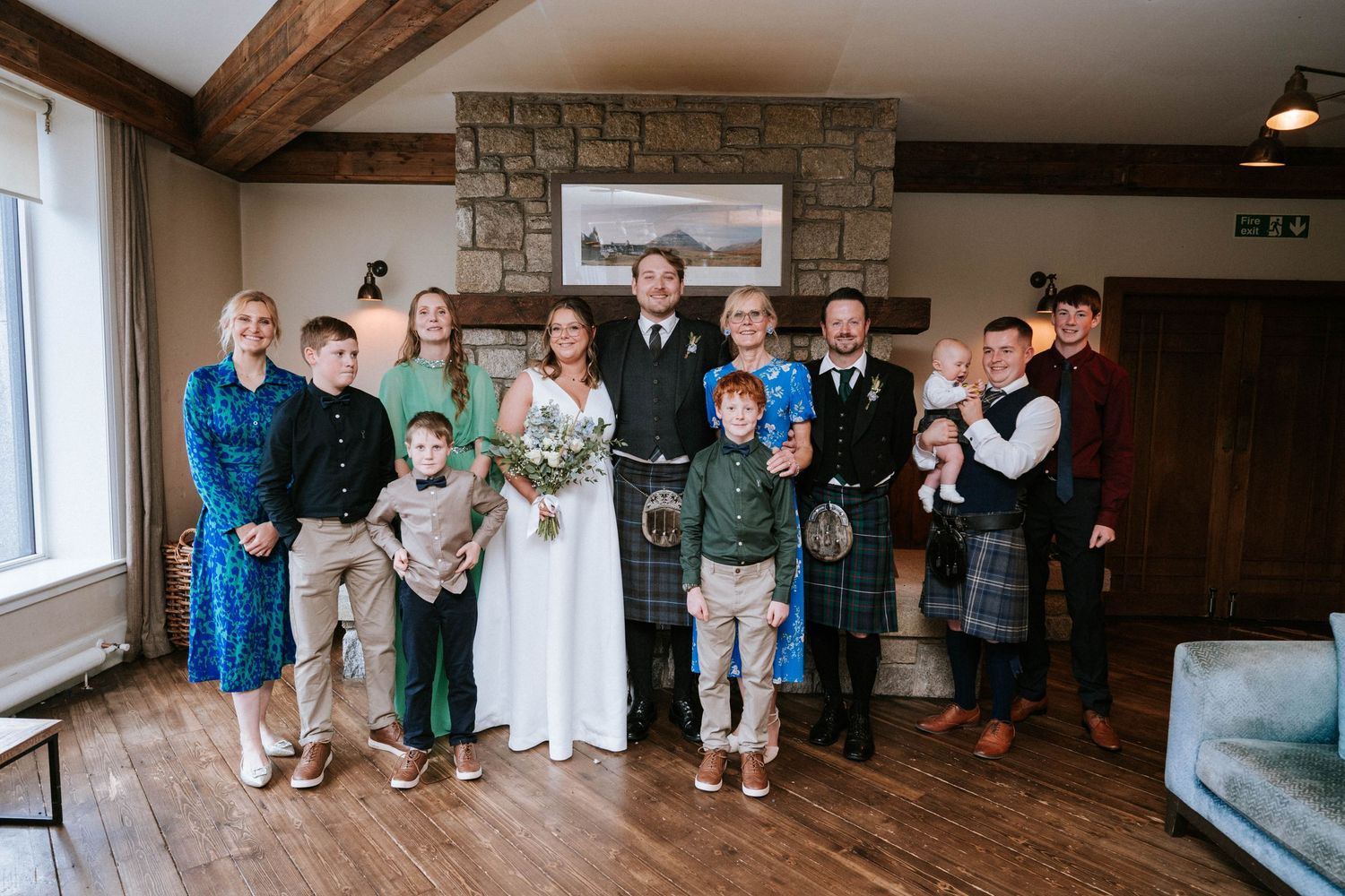 Wedding party poses in a rustic wooden interior venue with exposed beams and stone walls.