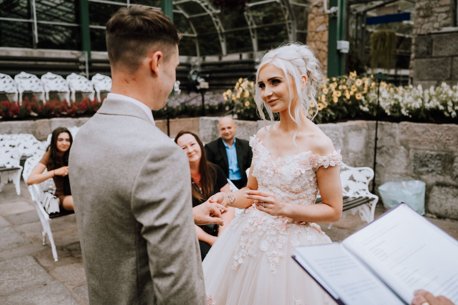 A couple exchanges rings during an intimate greenhouse wedding ceremony.