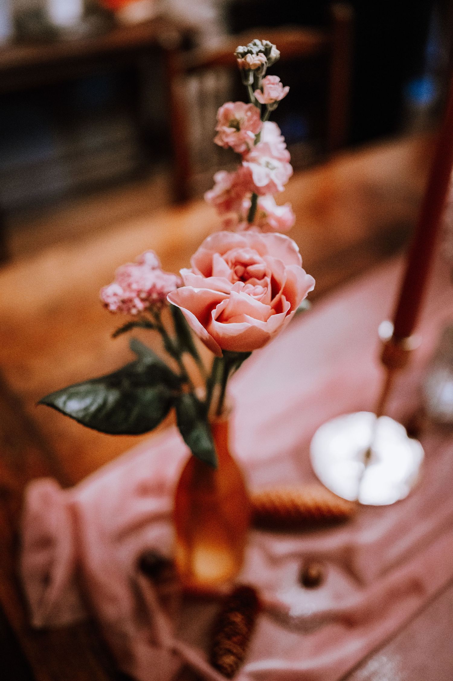 Delicate pink roses in an amber-colored vase on a soft fabric draped surface.