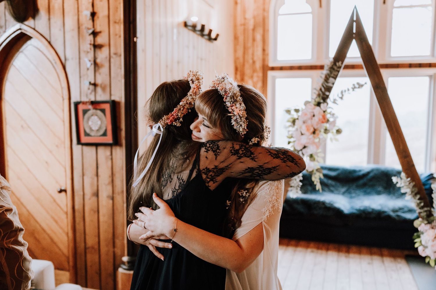A couple embraces during an intimate wedding ceremony in a rustic wooden chapel with natural lighting.