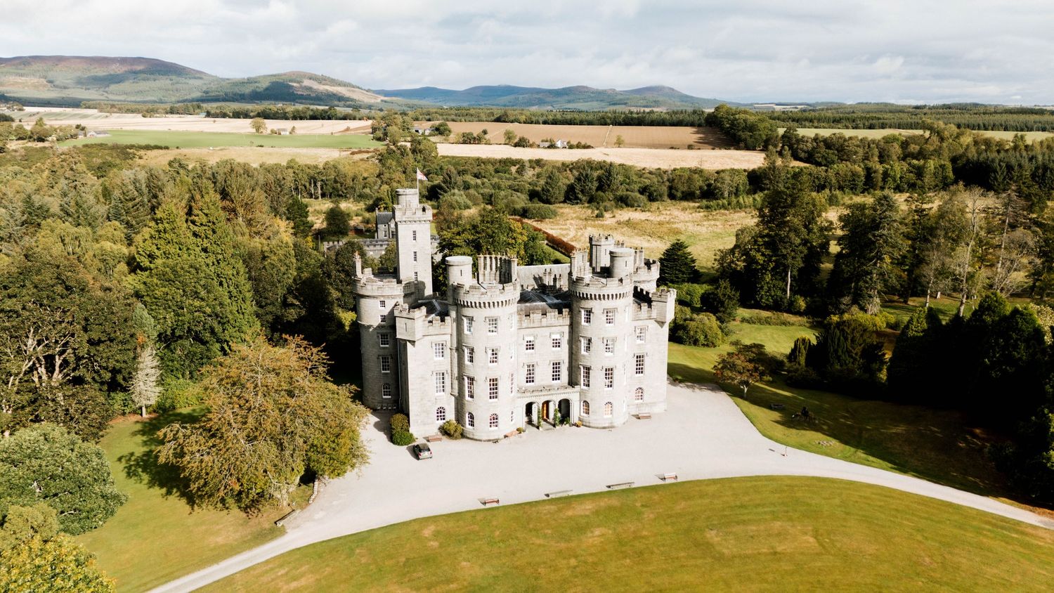 Aerial panorama of a historic castle estate surrounded by Scottish countryside and farmland.