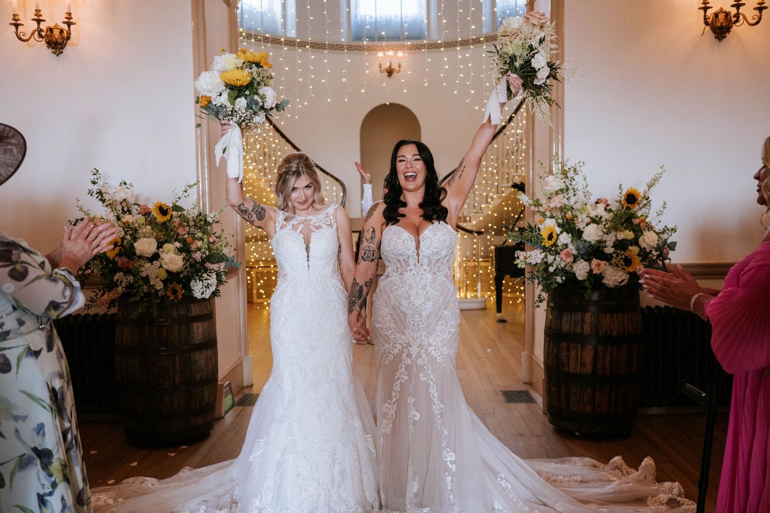 Fasque Castle Wedding Photography. Two brides share an intimate moment in an elegant indoor venue with chandeliers and floral decorations.