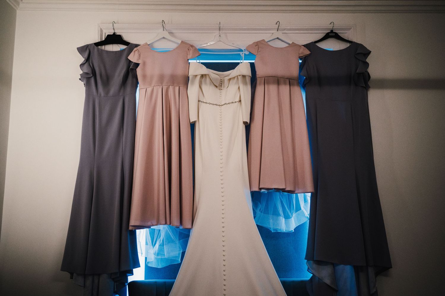 A clothing rack displaying formal dresses in navy, beige and black colors.
