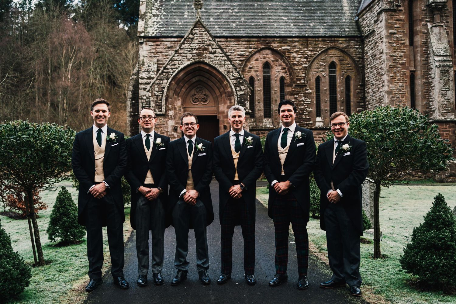 Aberdeen Wedding Photography. Groomsmen in black suits lined up outside a historic stone church.